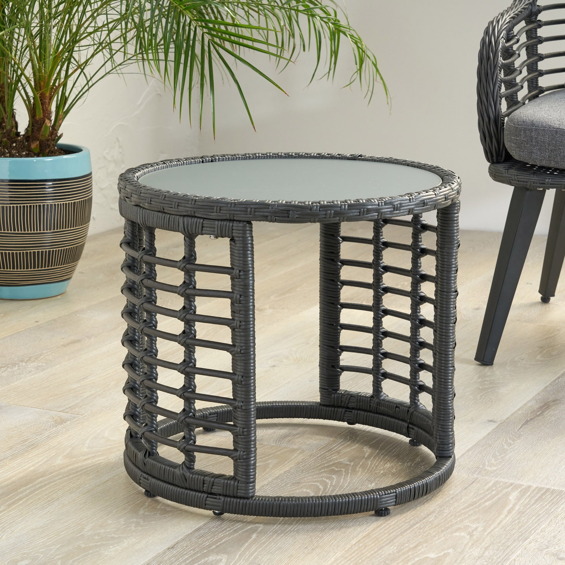 Dark gray wicker round side table with glass top on patio floor