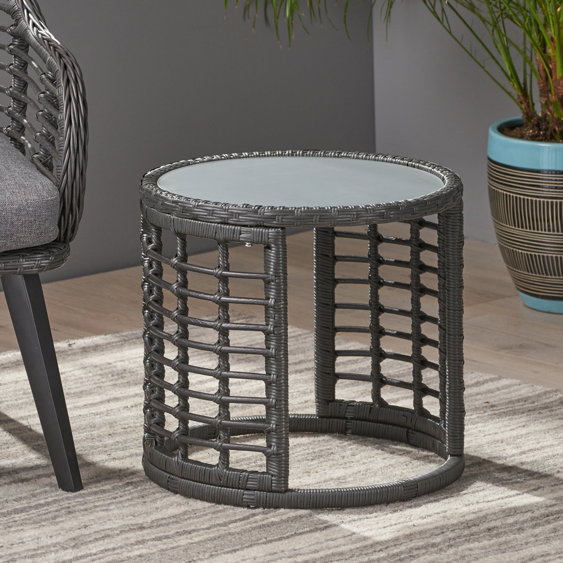Round grey wicker side table with a glass top perfect for patio use