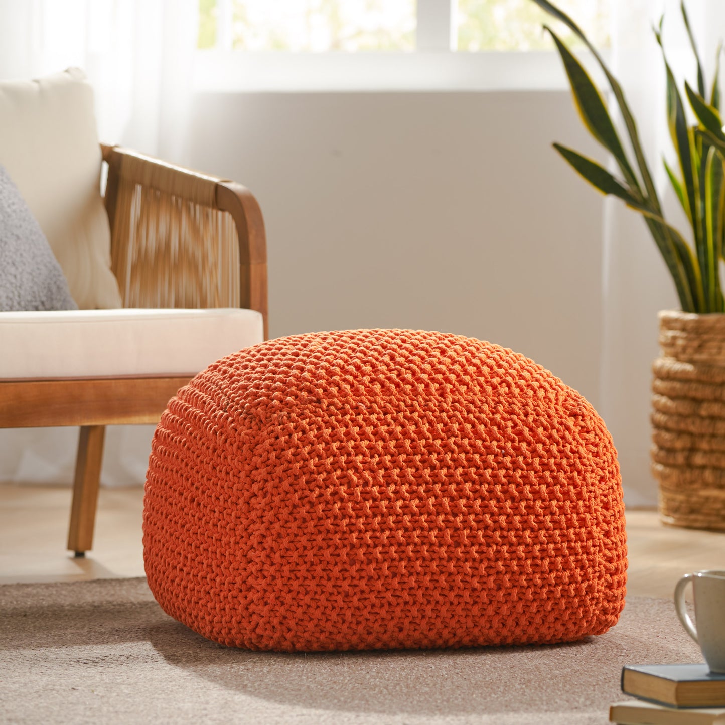 Orange knit pouf with textured yarn perfect for footrest or extra seating