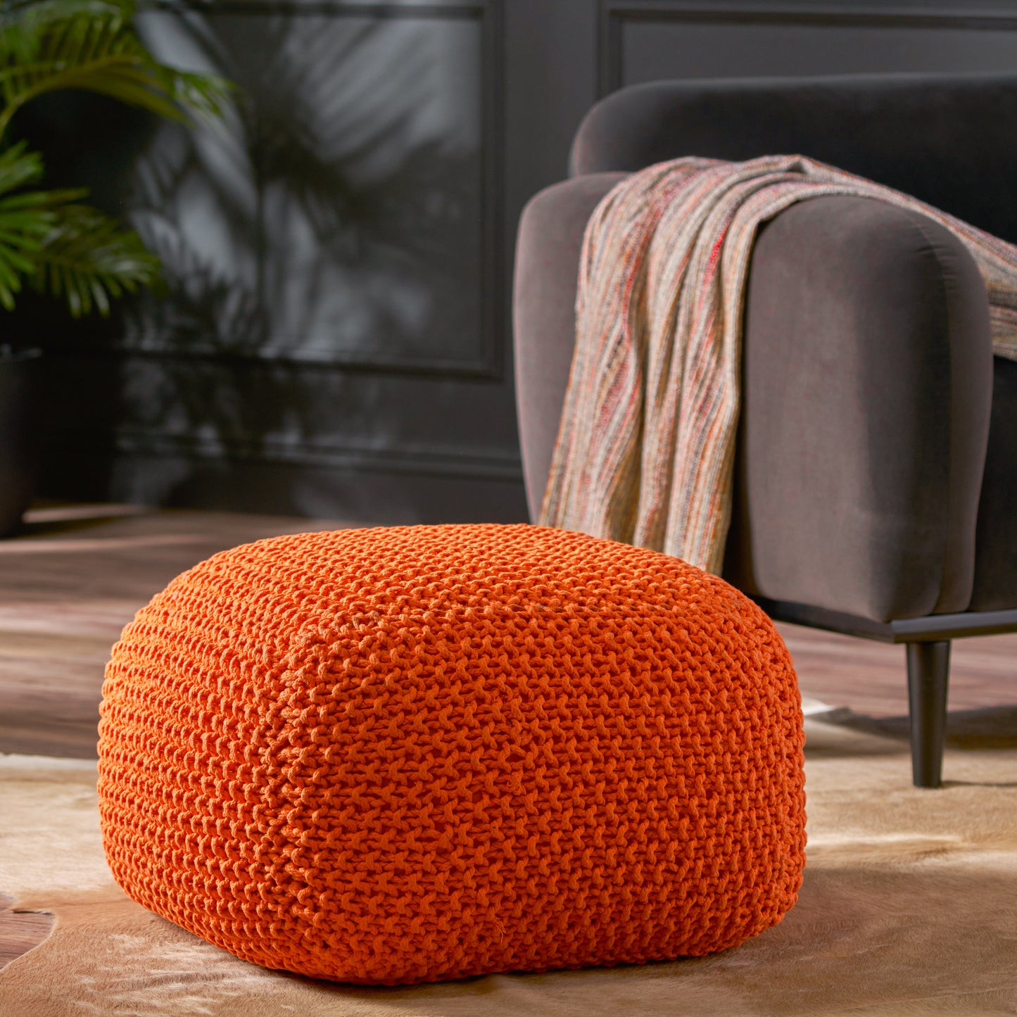 Vibrant orange knitted pouf with intricate texture perfect as a footrest