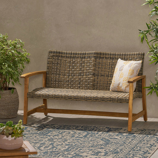 Woven grey rattan loveseat with wooden frame and decorative throw pillow perfect for outdoor seating