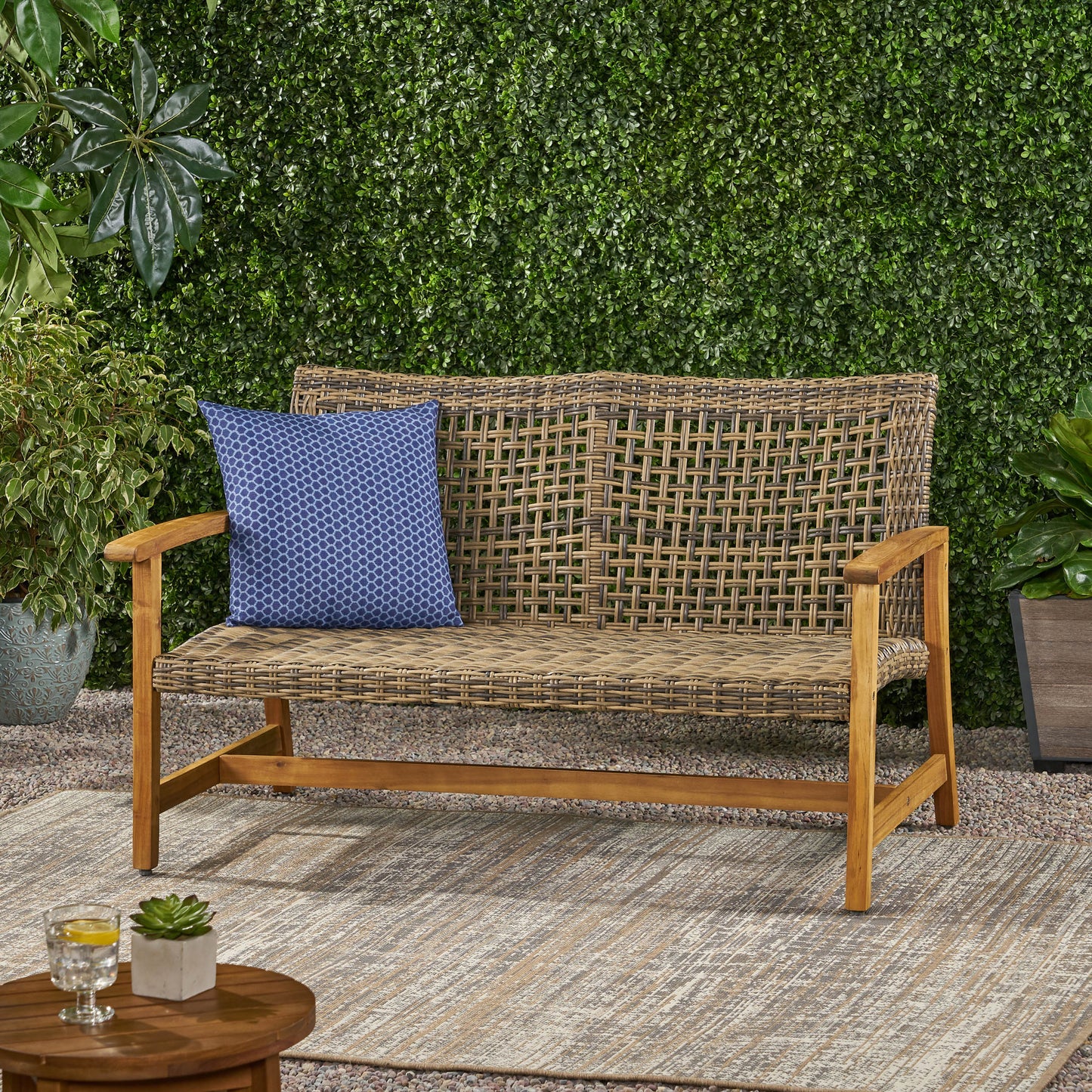 Brown rattan outdoor bench with wooden frame and blue patterned cushion