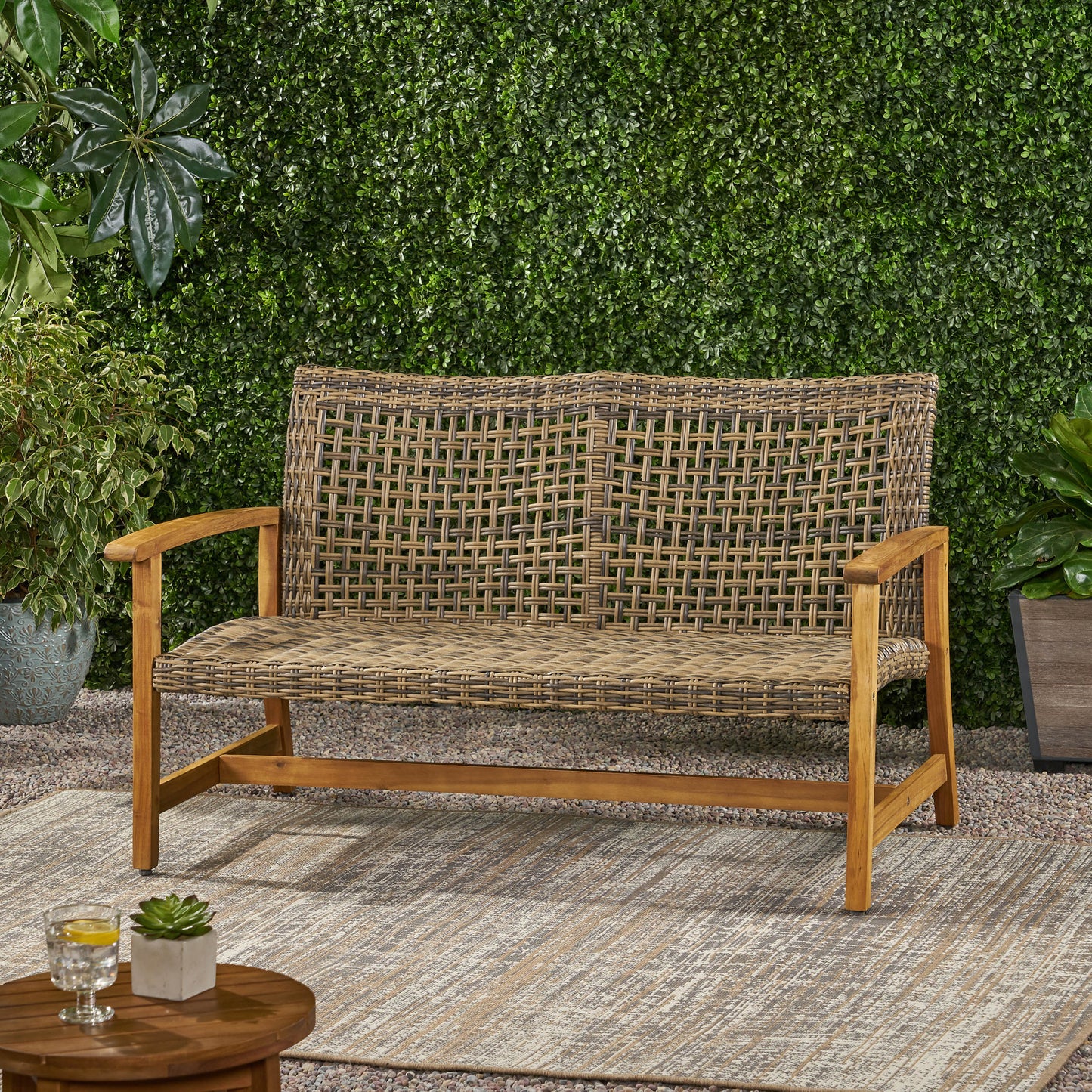 Brown and beige wicker outdoor bench with wooden frame and armrests perfect for patios