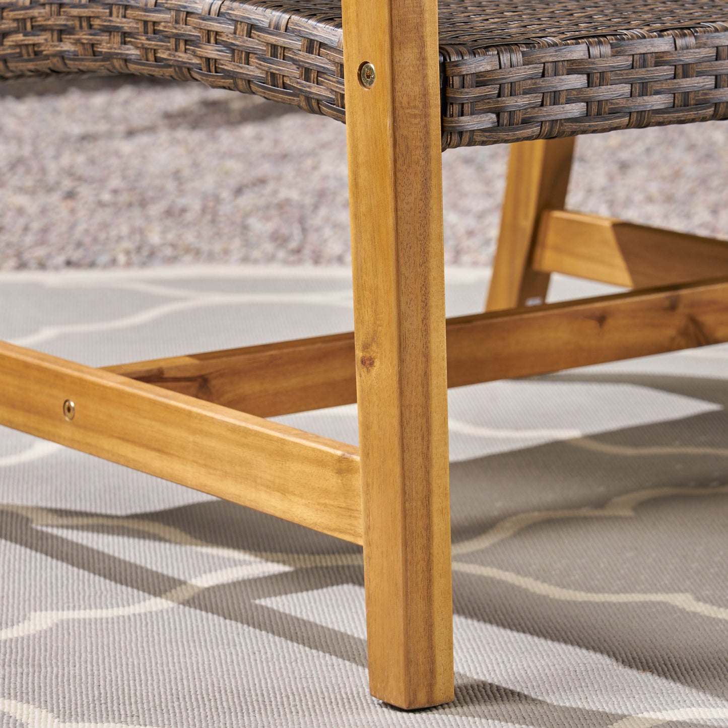 Woven brown rattan seat detail on acacia wood outdoor chair leg