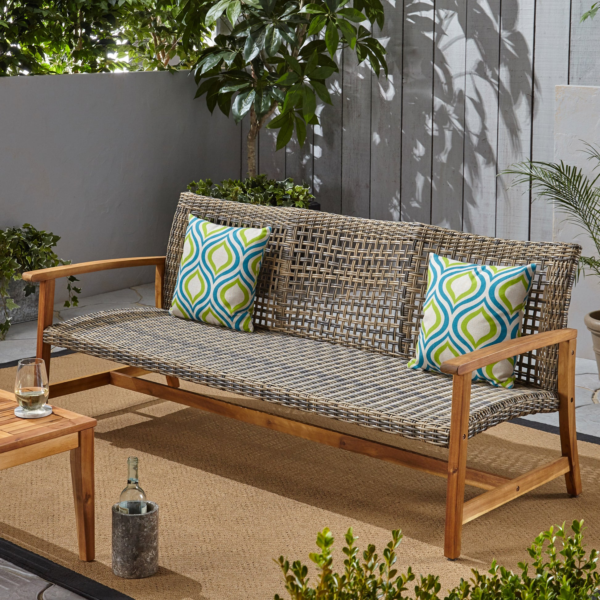 Woven wicker outdoor bench with wooden frame and geometric patterned cushions