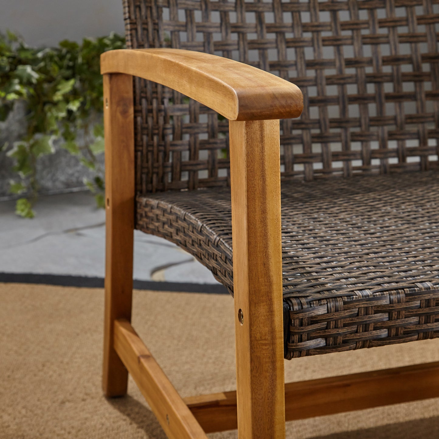 Closeup of dark brown rattan weave chair with wooden armrest and legs