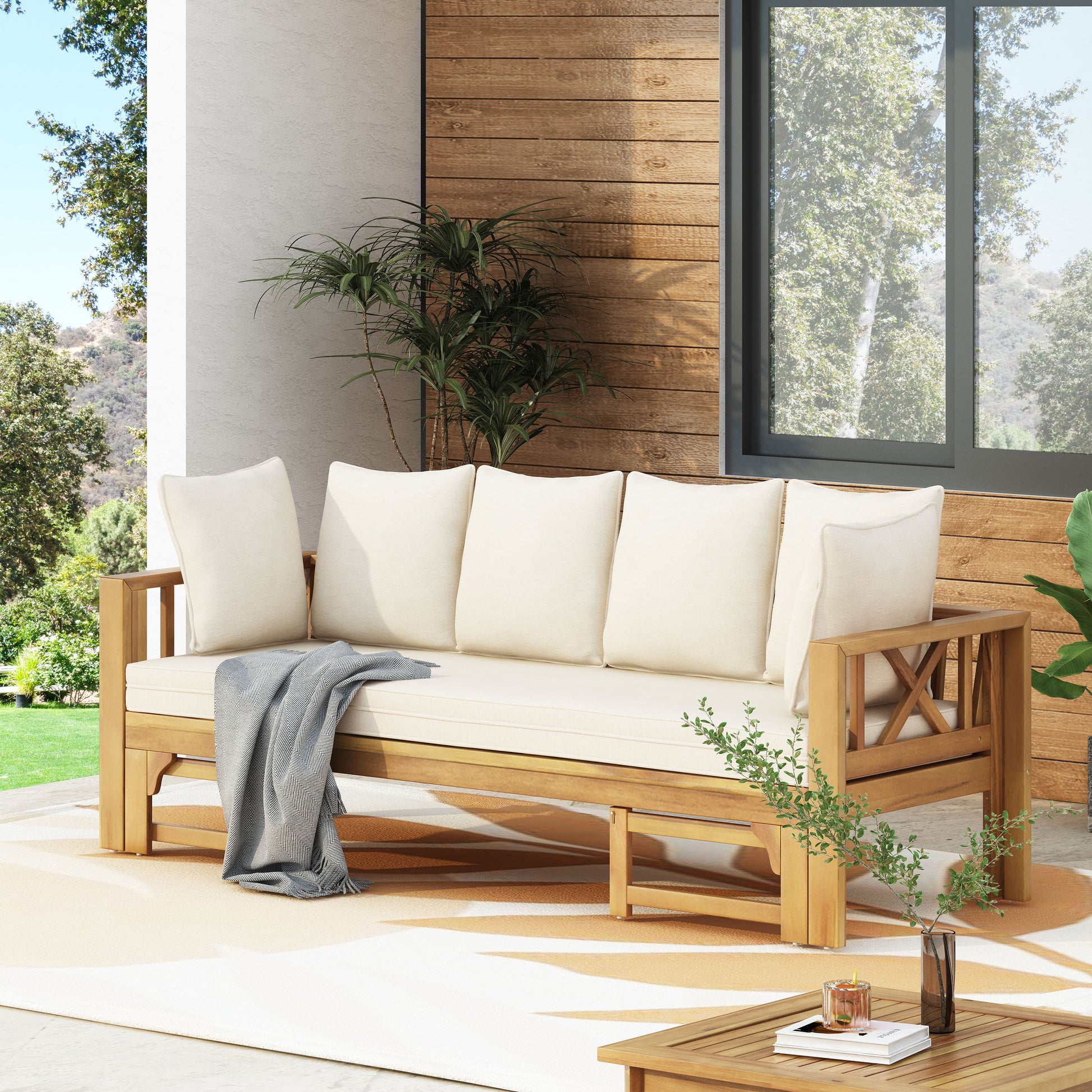 Wooden outdoor sofa with cream cushions and grey throw blanket