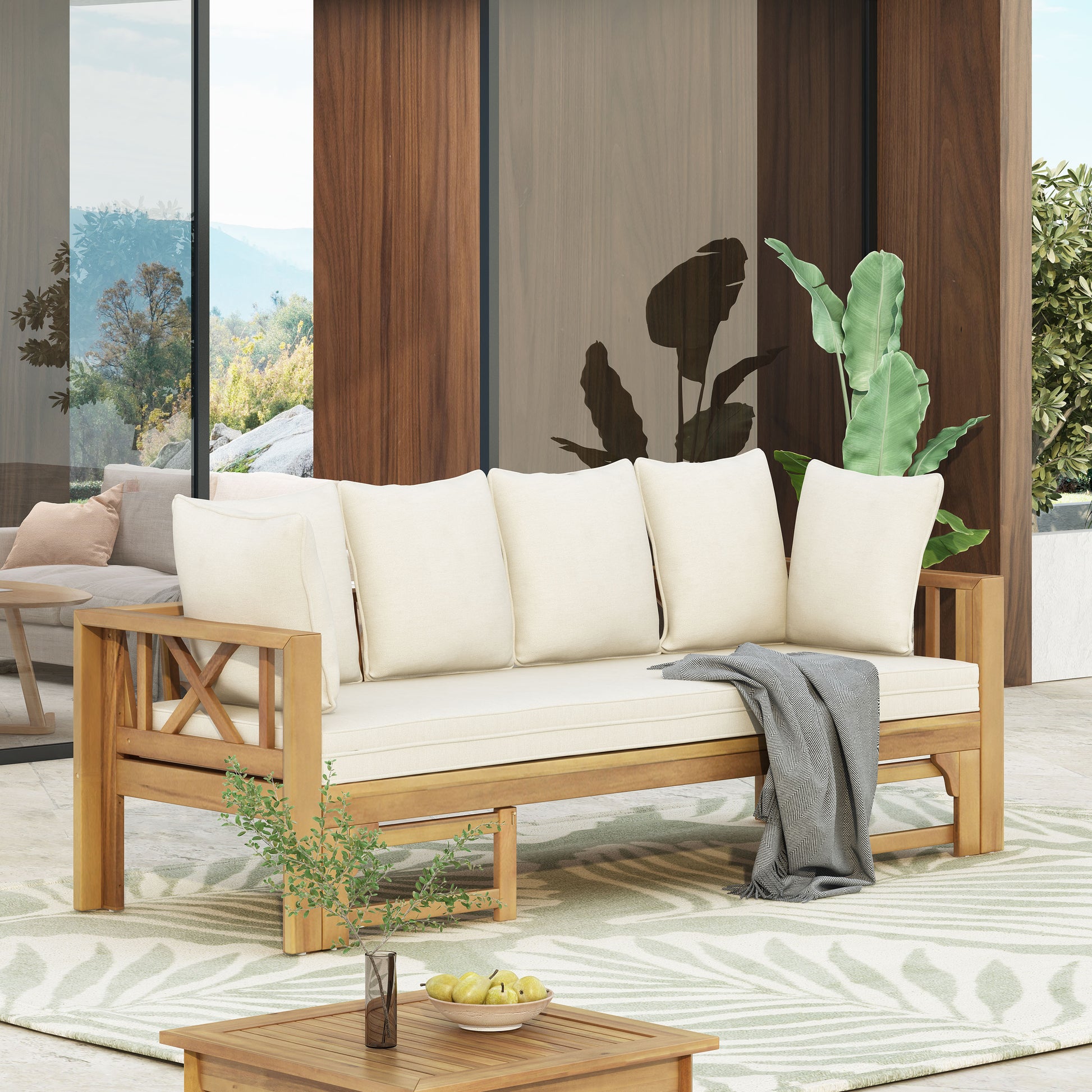 Wooden outdoor sofa with cream cushions and a grey throw ideal for patio relaxation