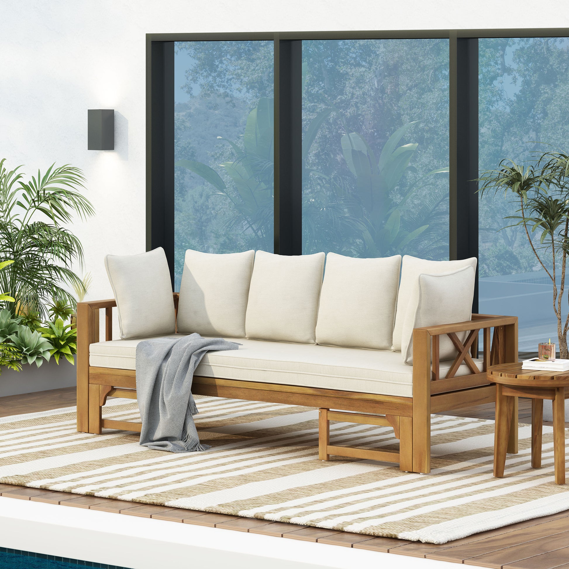 Wooden outdoor sofa with cream cushions and a gray throw blanket
