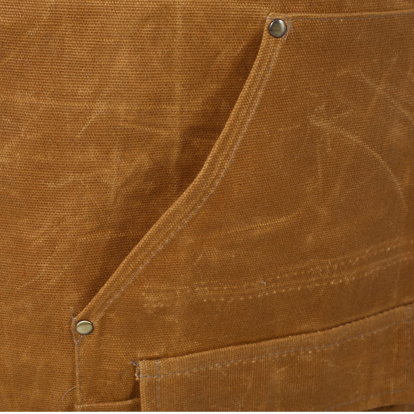 Closeup of tan canvas fabric showing stitch details and metal snap buttons on workwear