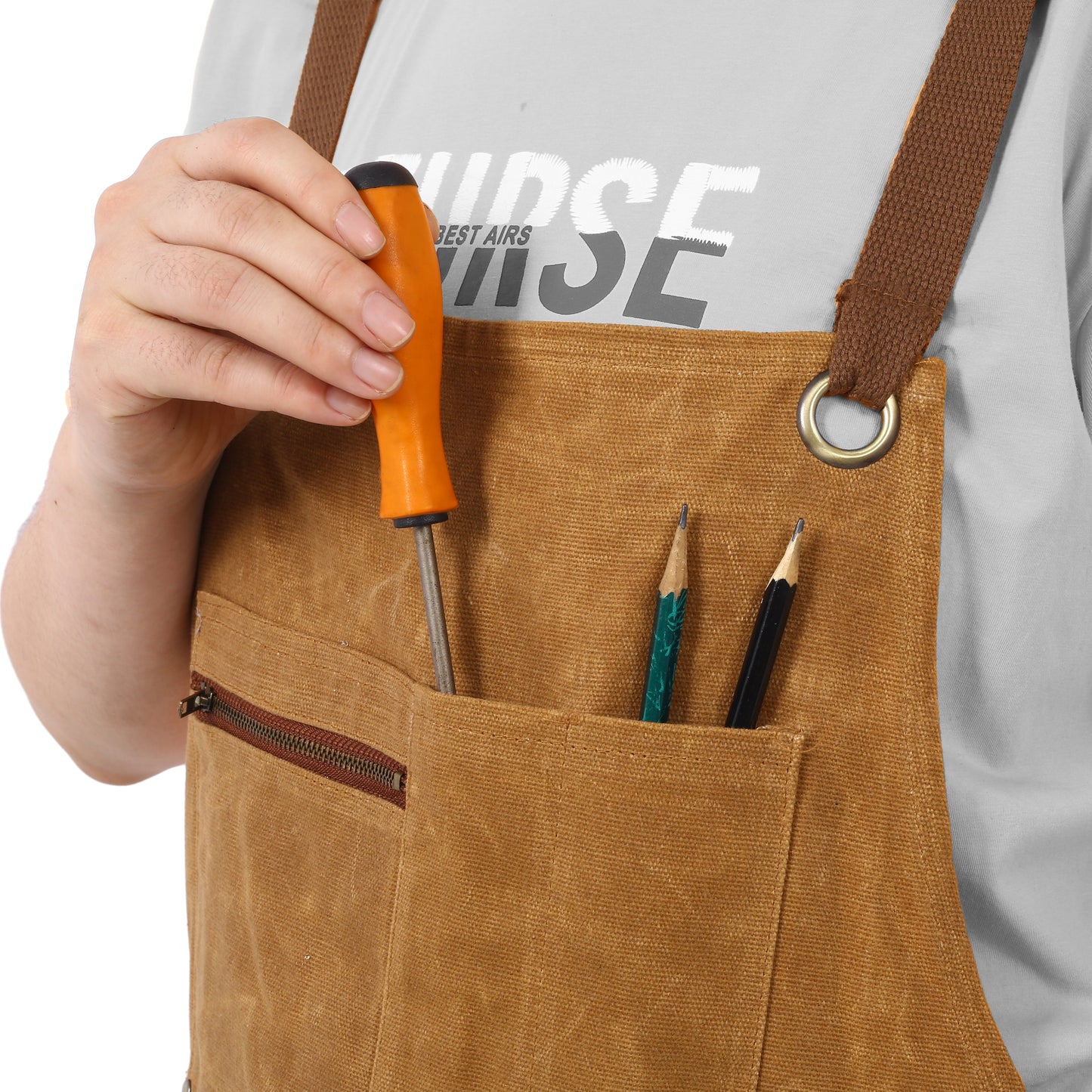 Canvas work apron in tan with brown strap and brass grommet holding screwdriver and pencils