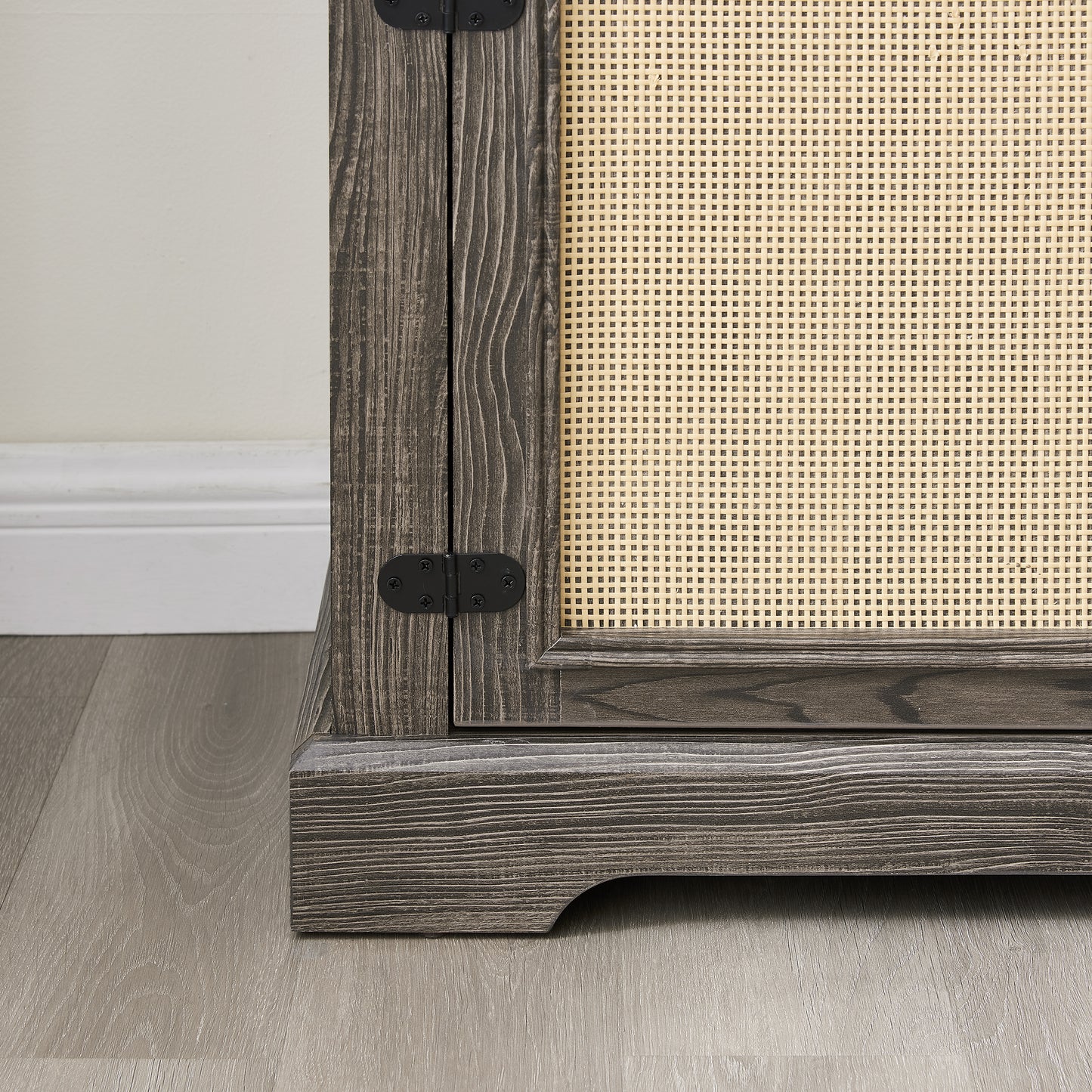 Dark wood cabinet detail with woven cane panel and black metal hinges