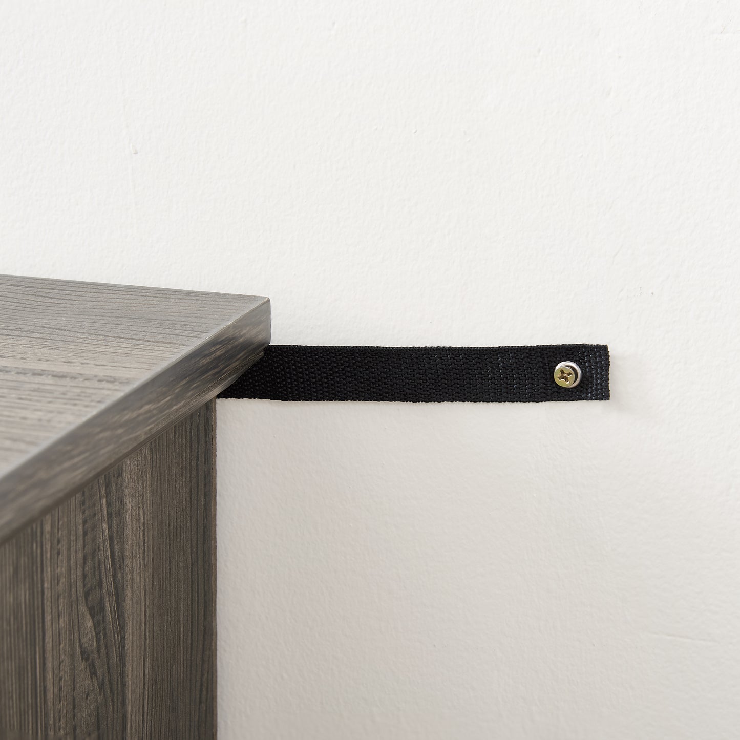 Gray wood shelf with a black antitip strap secured to the wall