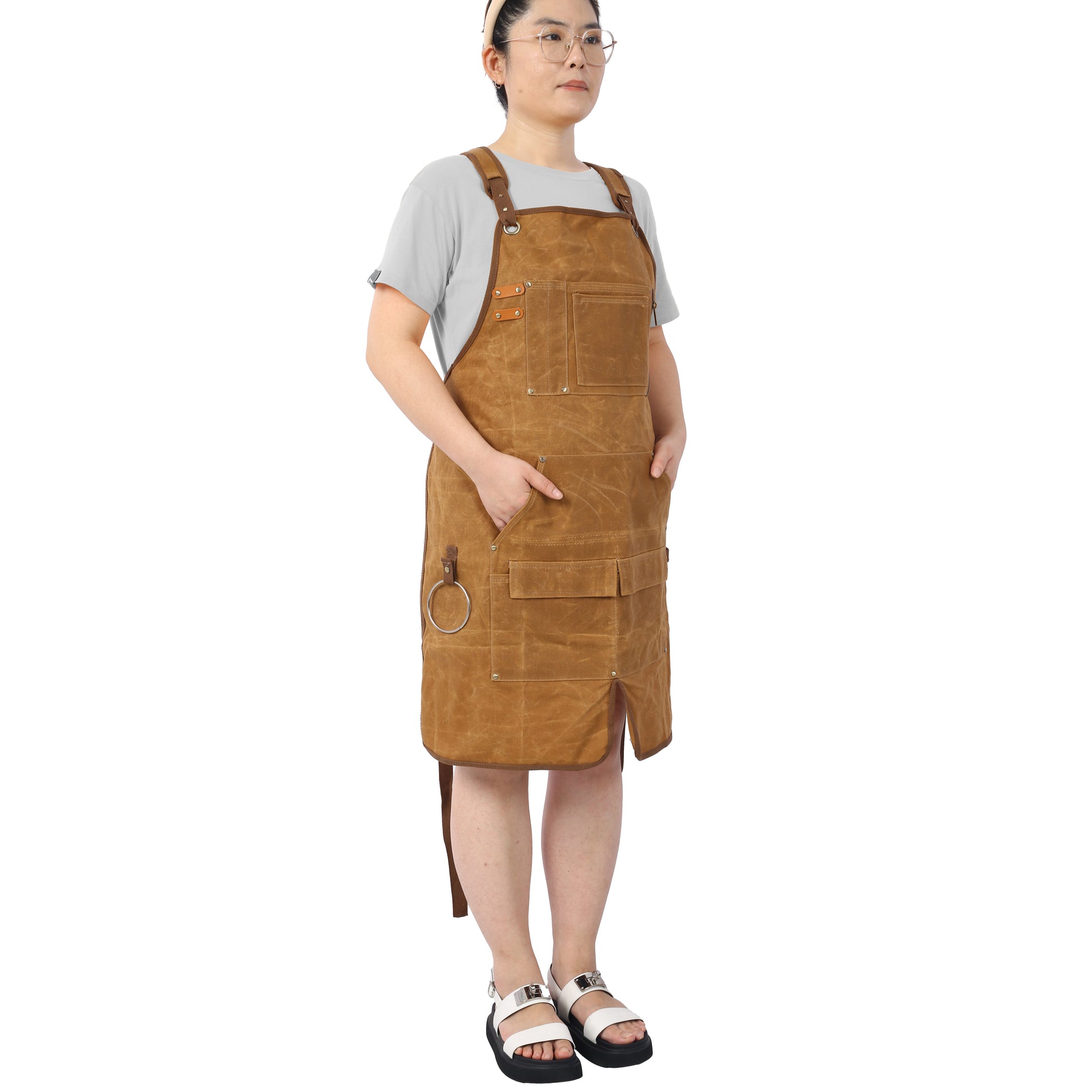 Brown canvas utility apron with leather straps and multiple pockets for artists