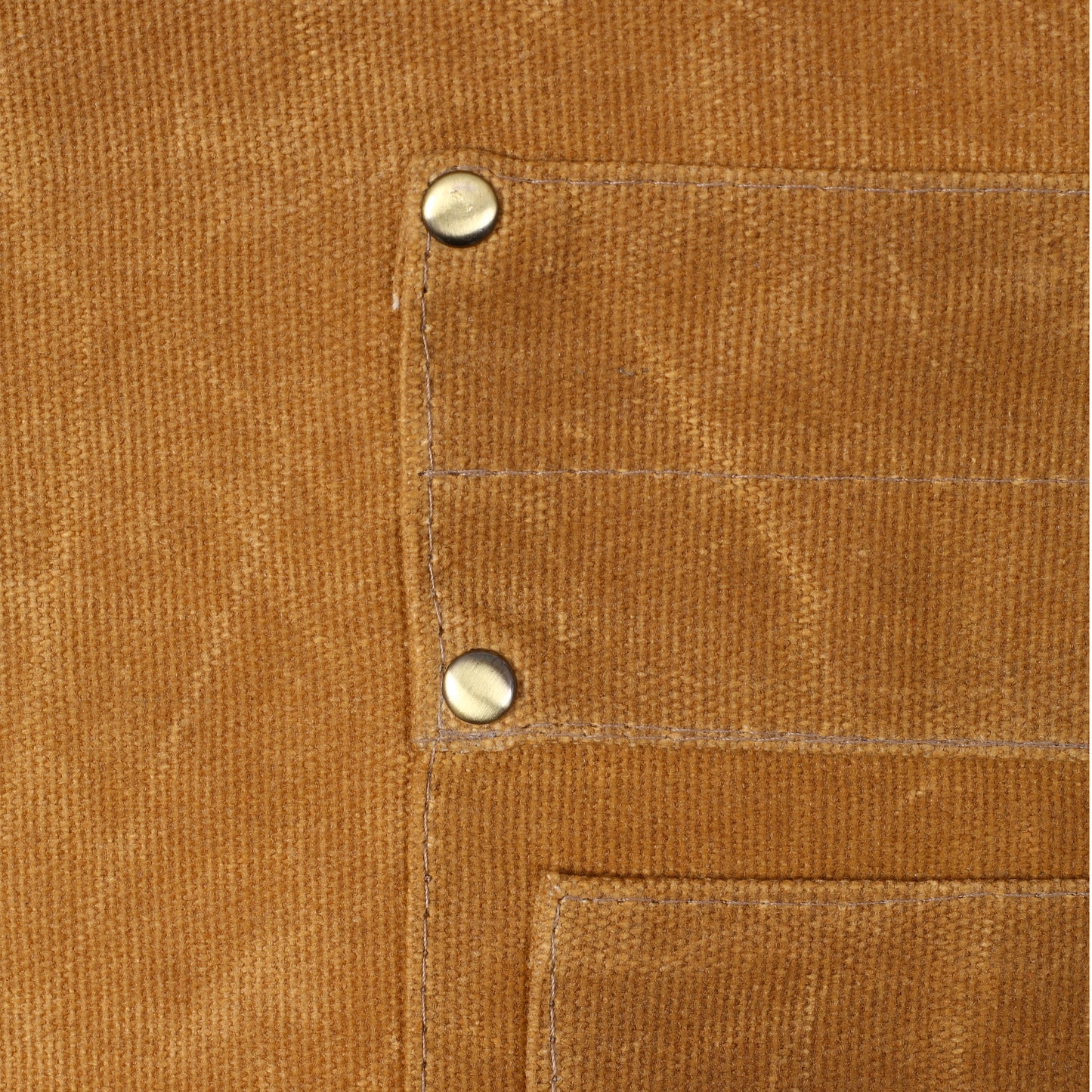 Closeup of tan canvas fabric with two metal rivets and visible stitching