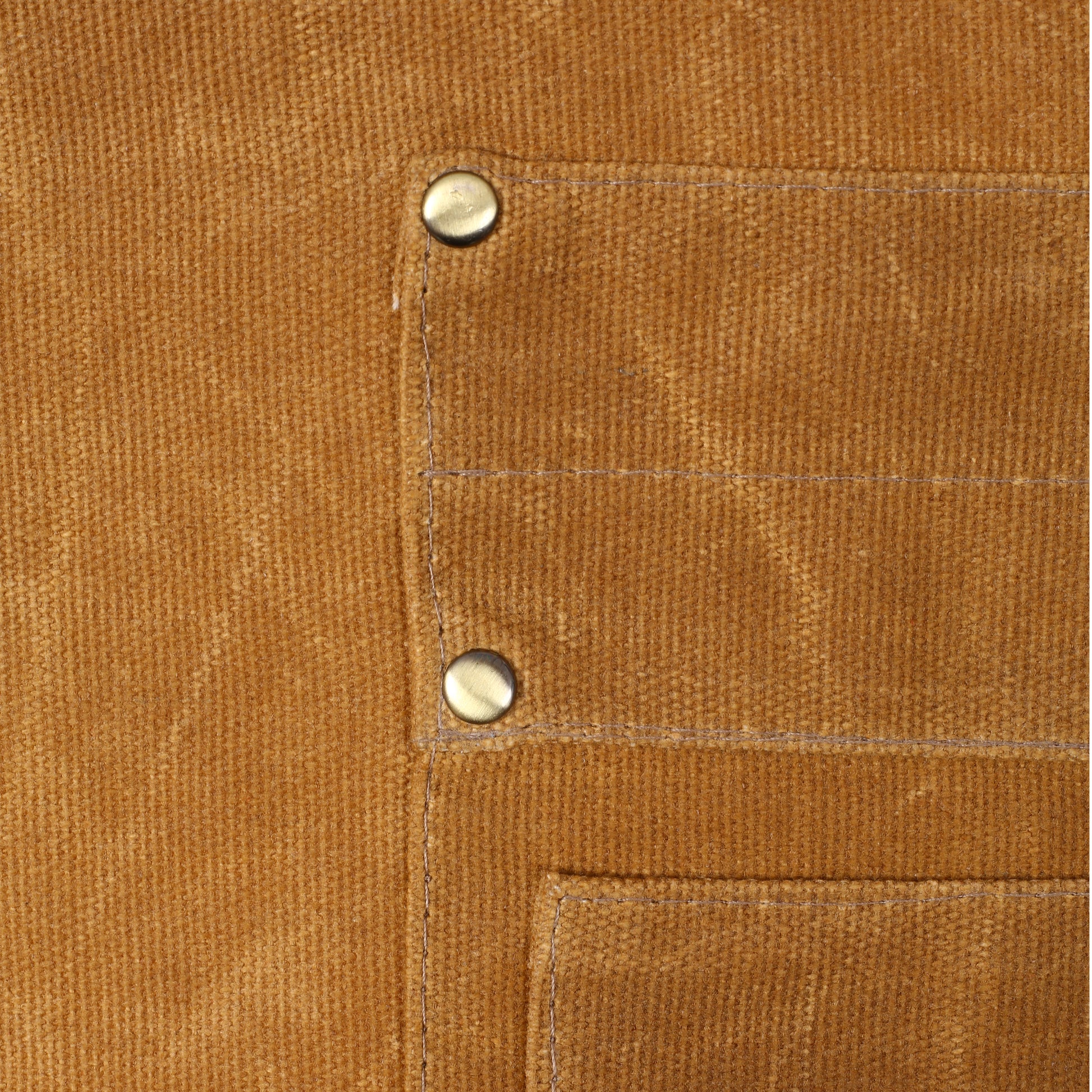 Closeup of tan canvas fabric with two metal rivets and visible stitching