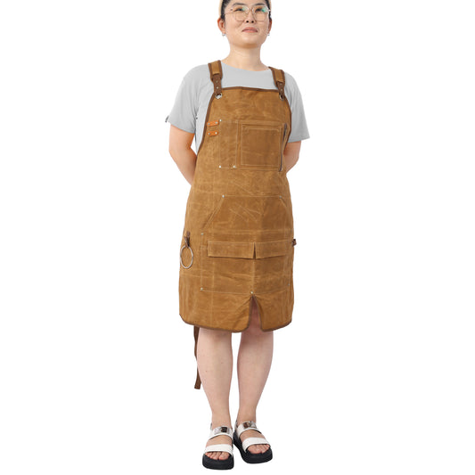 Brown canvas work apron with adjustable leather straps multiple pockets and a Dring detail for tools