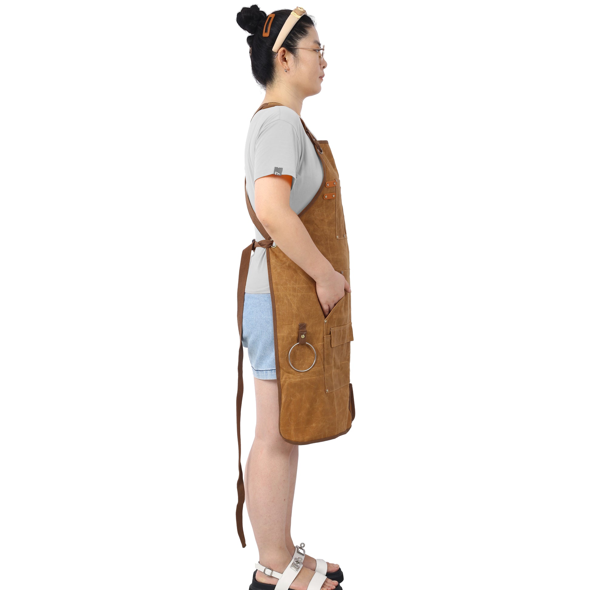 Brown canvas utility apron with multiple pockets and adjustable straps for versatile use
