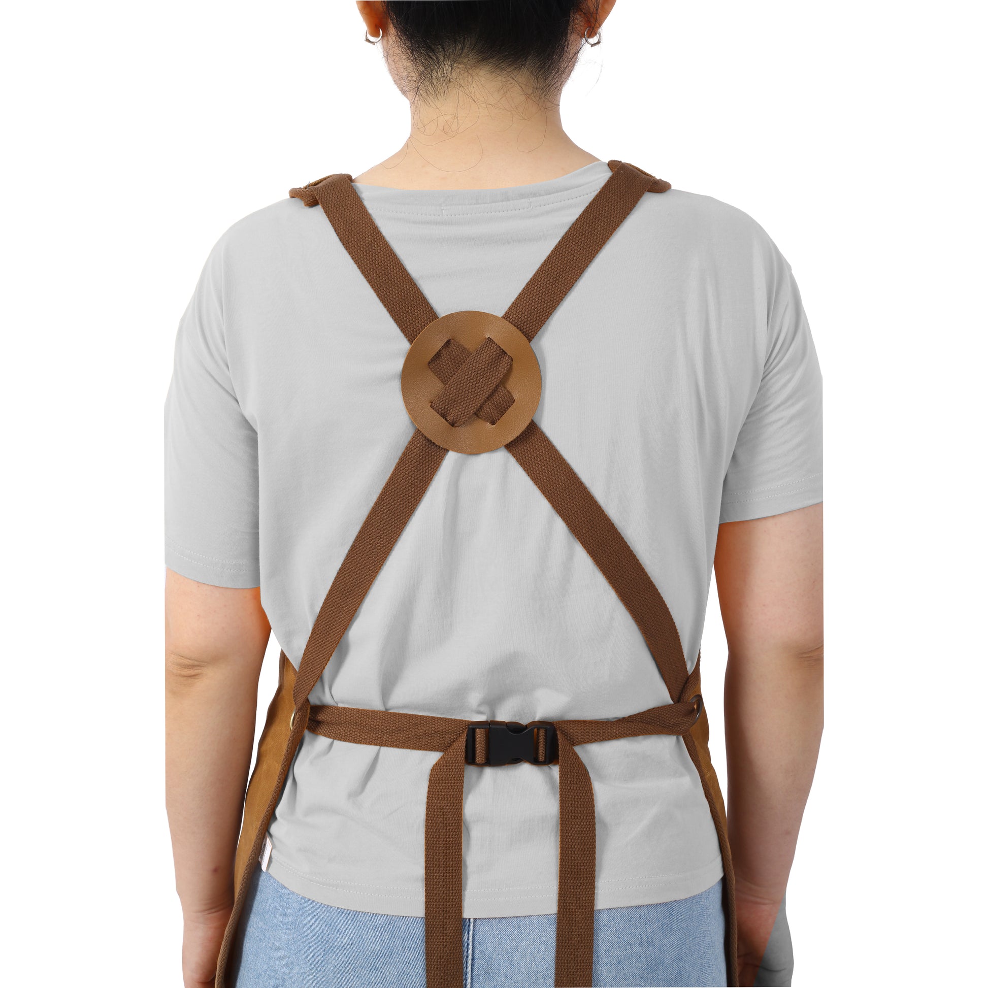 Brown canvas utility apron with adjustable crossback straps and leather detailing for comfort and durability