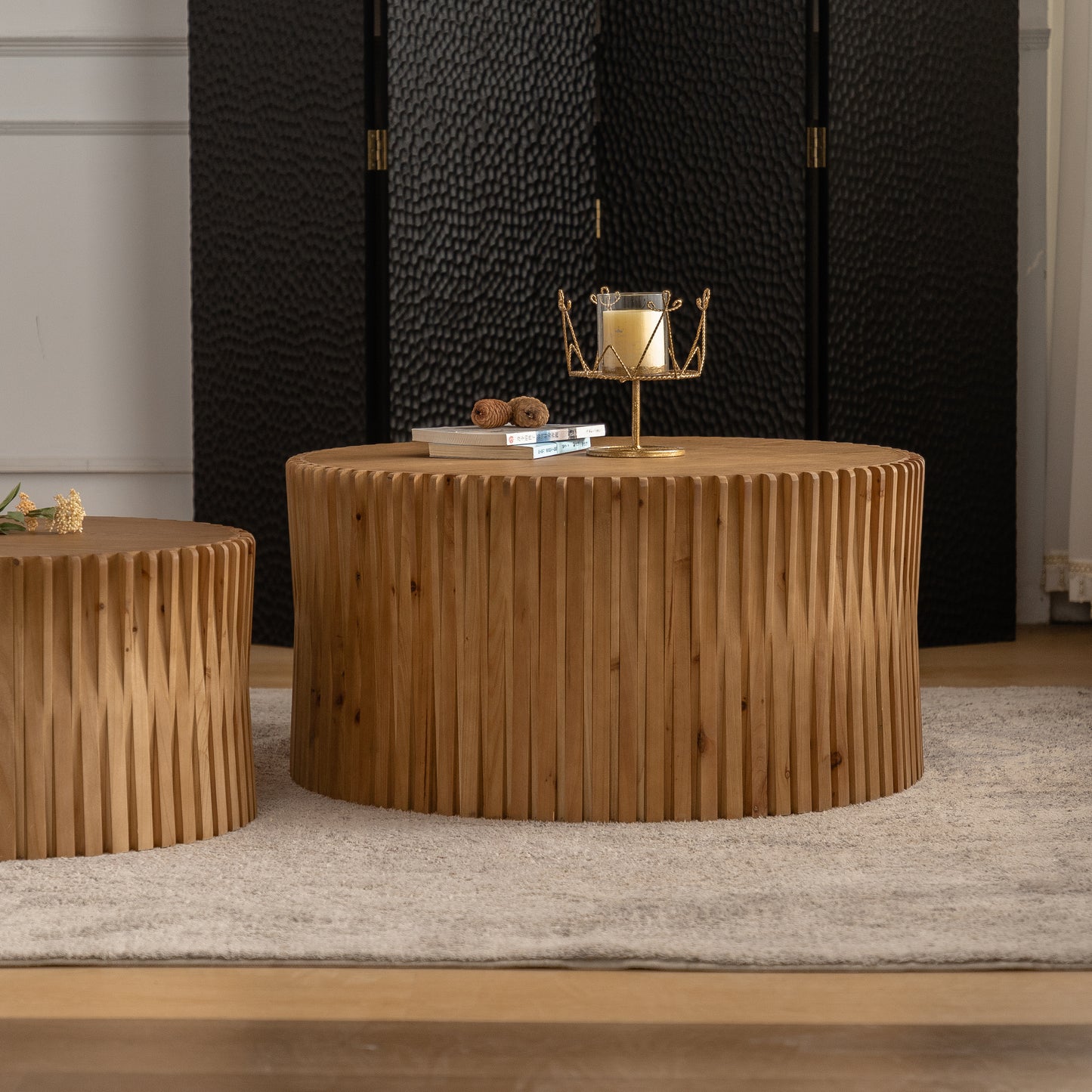 Round wooden coffee table with carved vertical planks and a cream rug