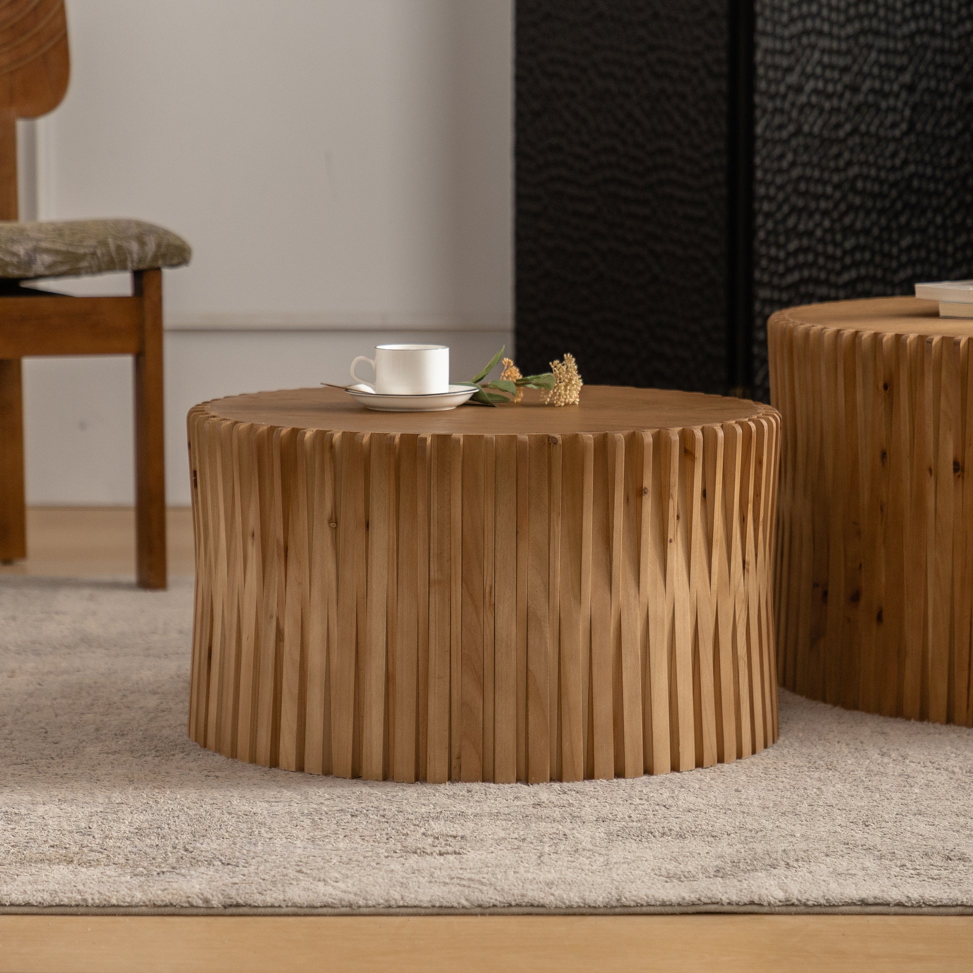 Round wooden coffee table with carved vertical wooden slats and a white cup on a saucer