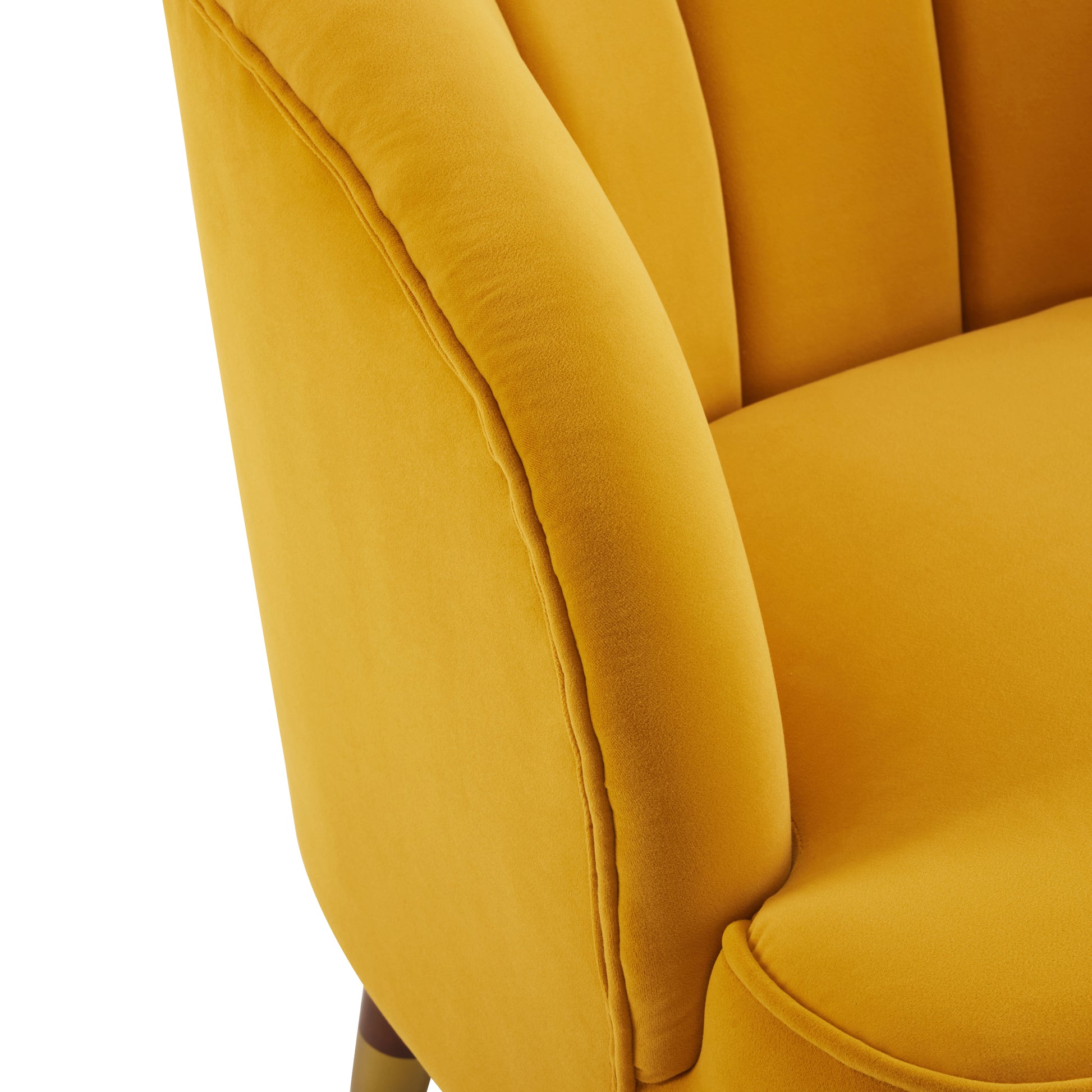 Closeup of a plush gold velvet armchair with channel tufting and piped seams