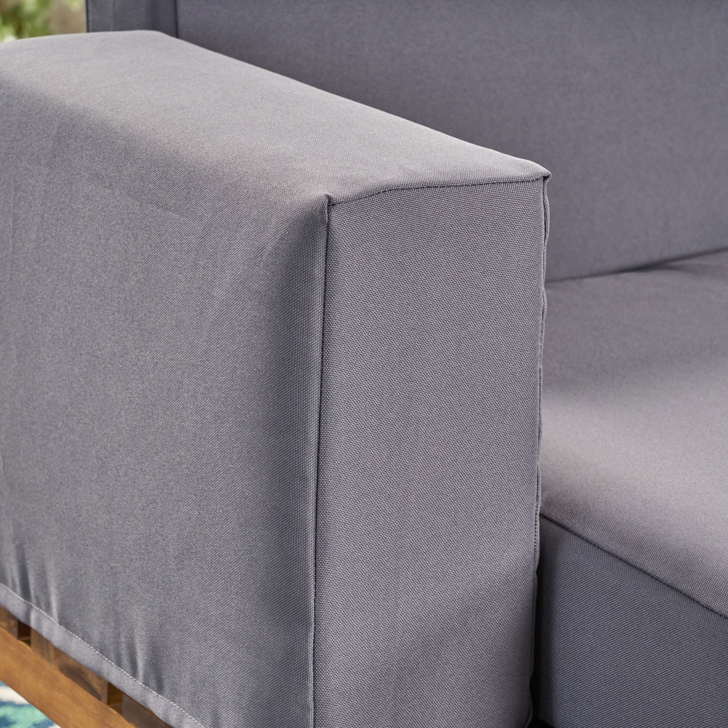 Closeup of a gray outdoor sofa armrest showcasing durable weatherresistant fabric texture