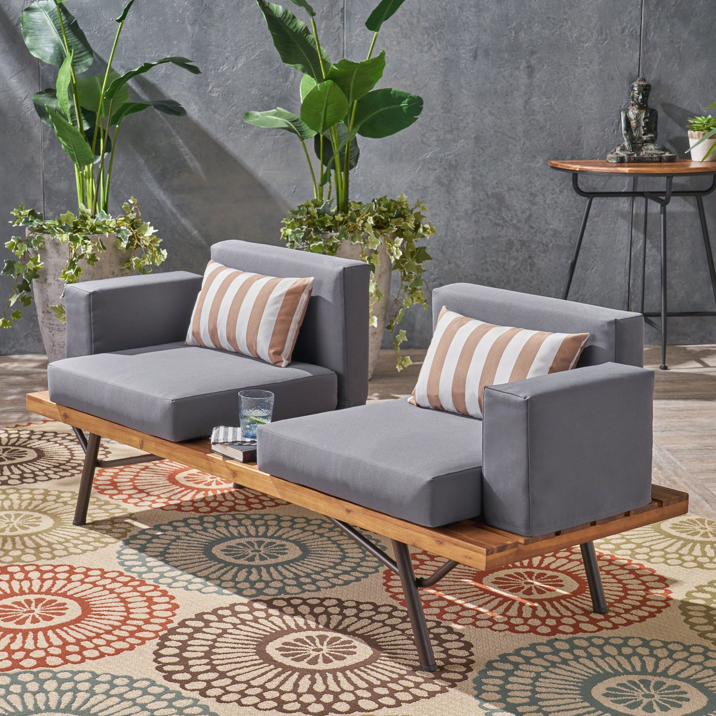 Gray outdoor modular sofa with striped throw pillows and wooden bench