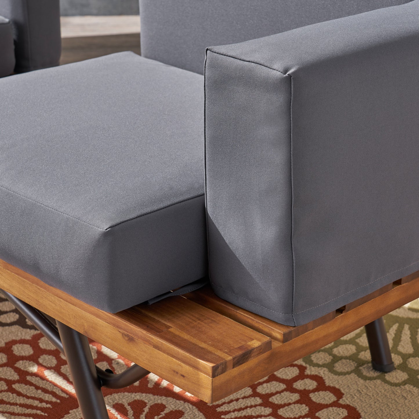 Closeup of grey fabric outdoor sofa cushions with a teak wood base modern design