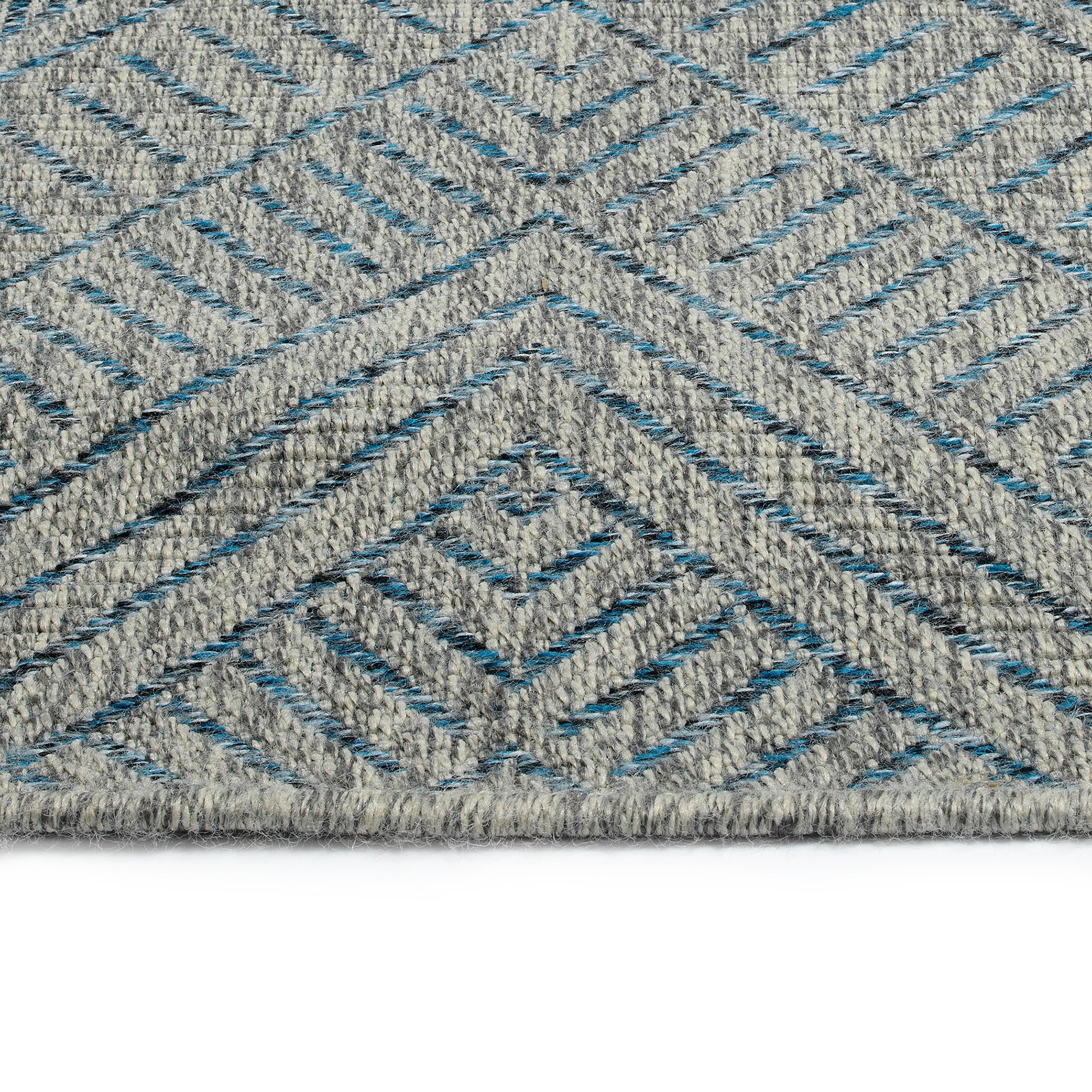 Closeup of a grey woven rug with a geometric diamond pattern in blue threads