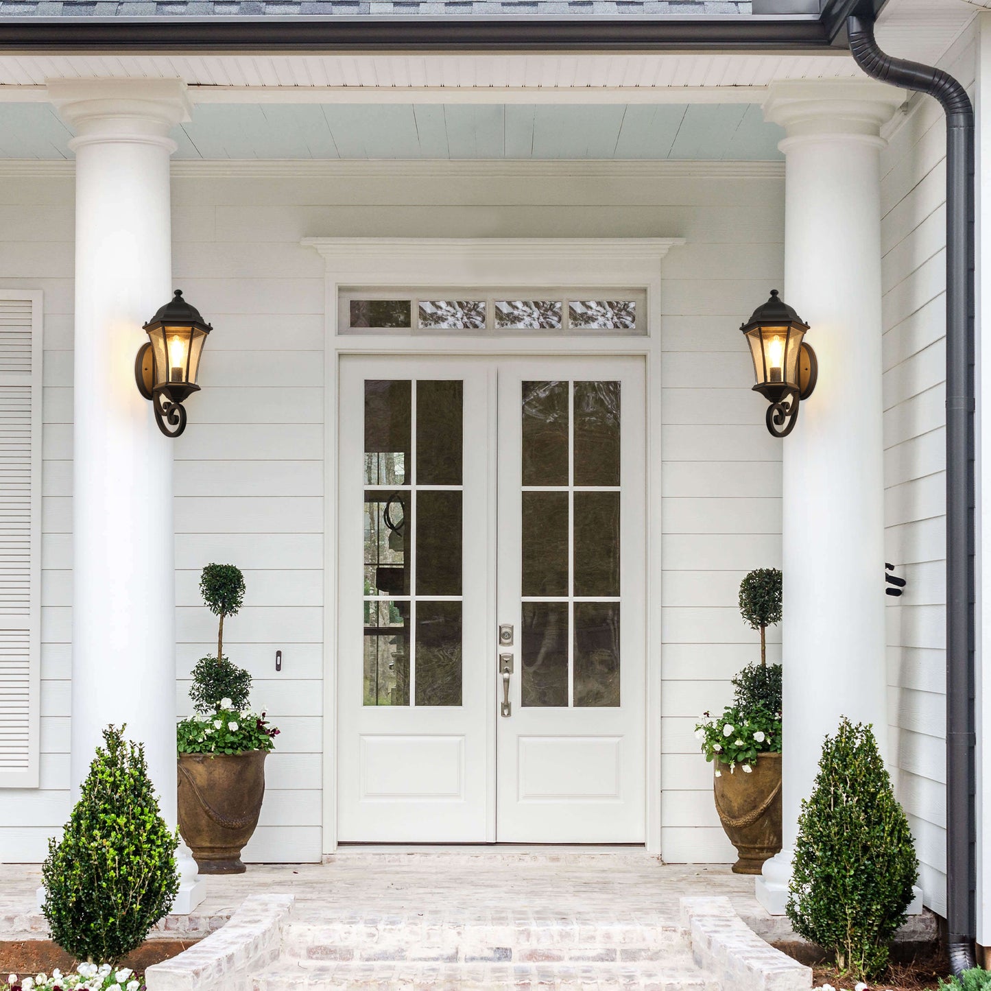 Black wrought iron outdoor wall lantern with seeded glass detail providing classic porch lighting