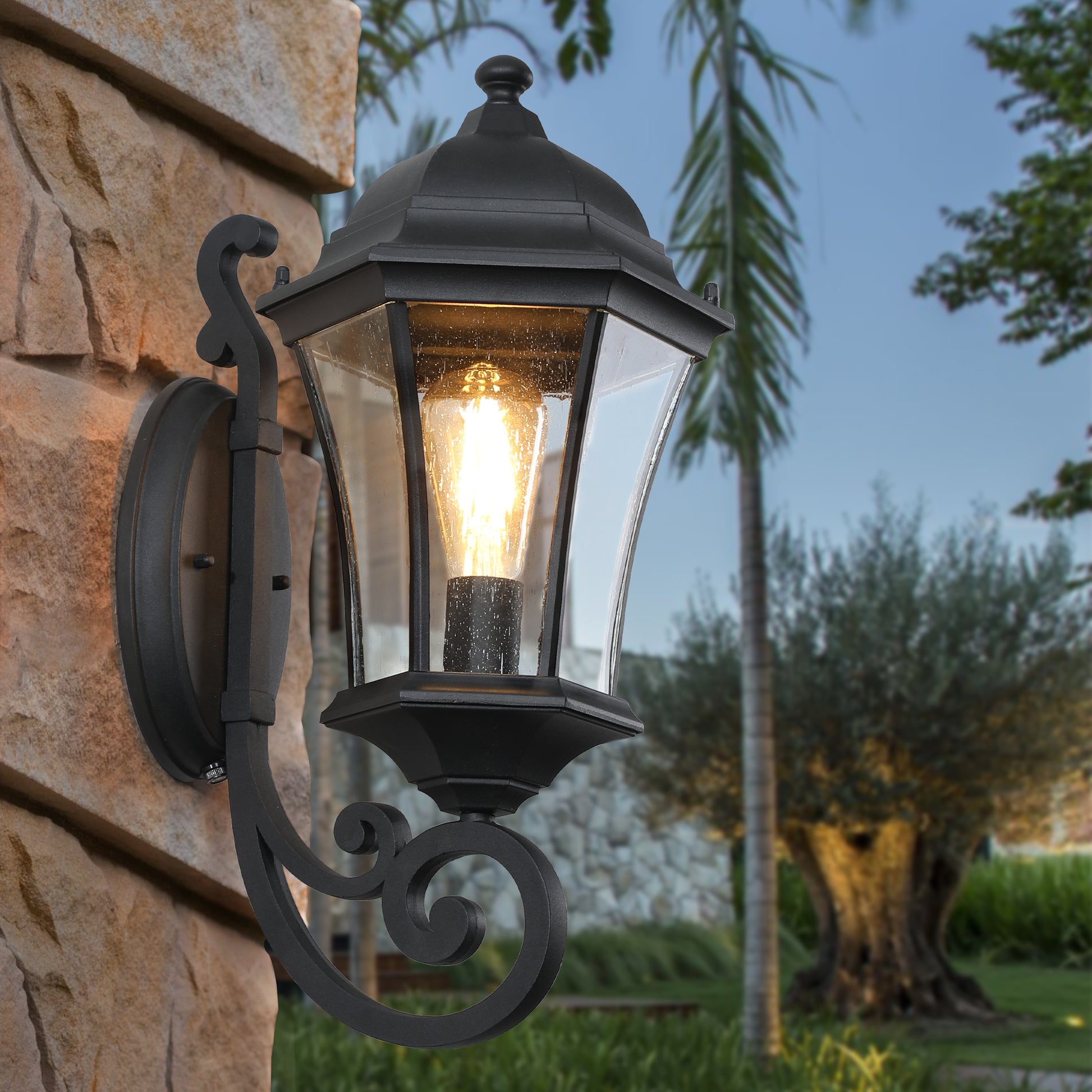 Black cast aluminum outdoor sconce with seeded glass and ornate scrollwork