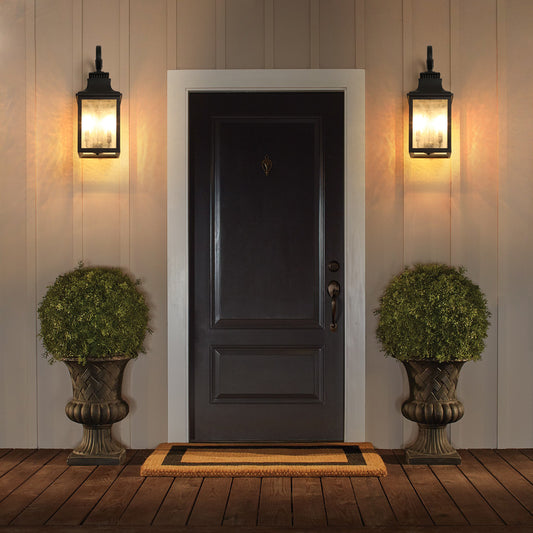 Traditional black outdoor wall lantern with frosted glass panels illuminating a porch