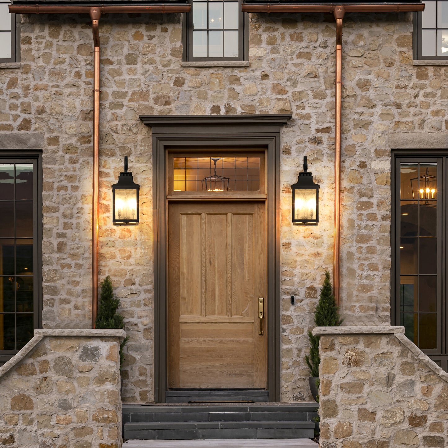 Rustic oak front door with a brass handle set in a natural stone facade