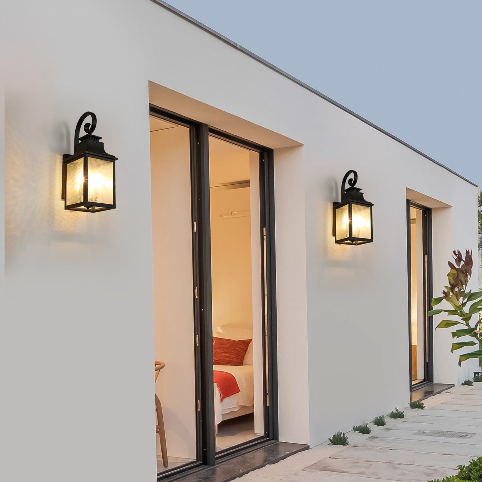 Traditional black outdoor lantern with clear glass panels illuminating a modern homes exterior wall