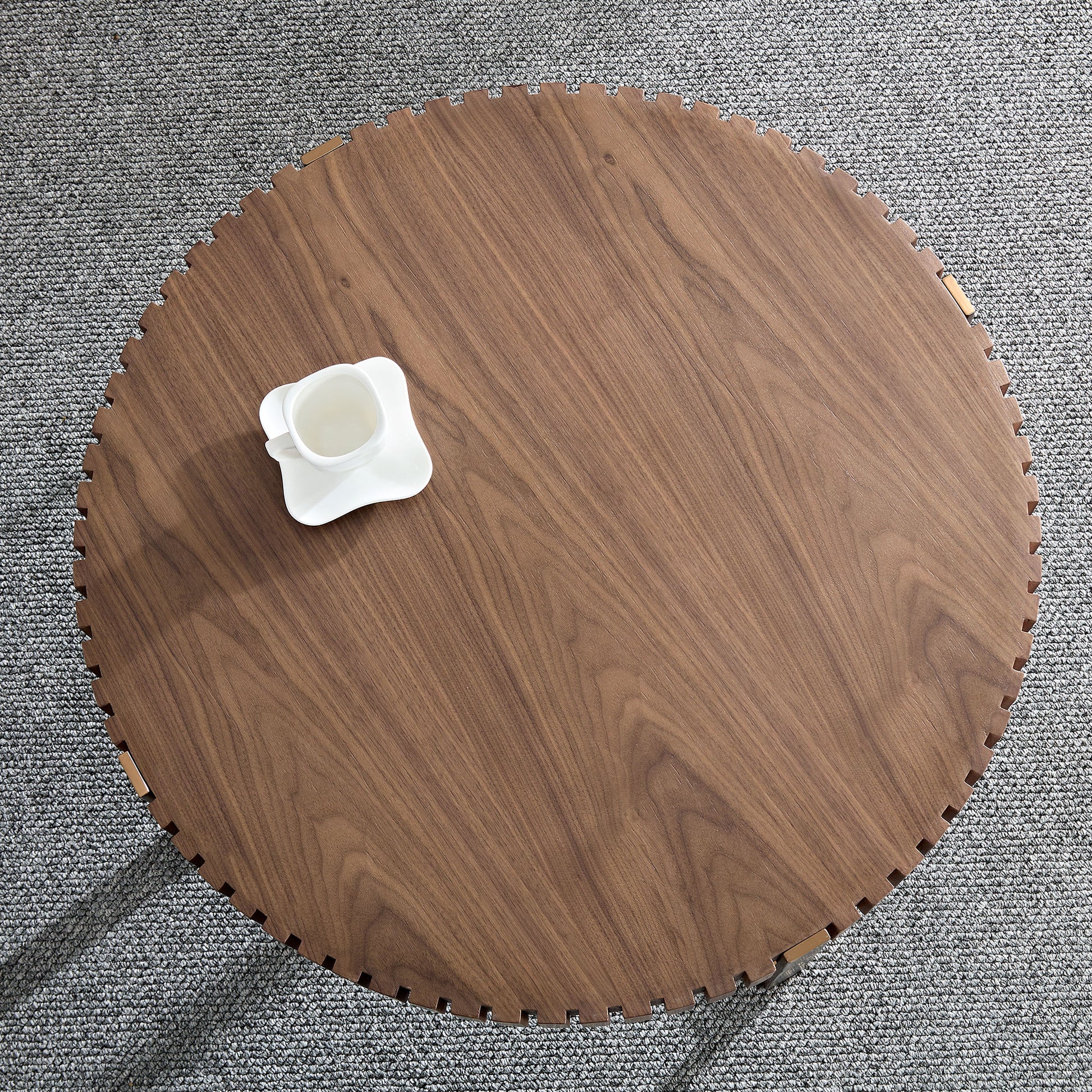 Round walnut coffee table with a decorative notched edge and a white teacup perfect for modern living rooms