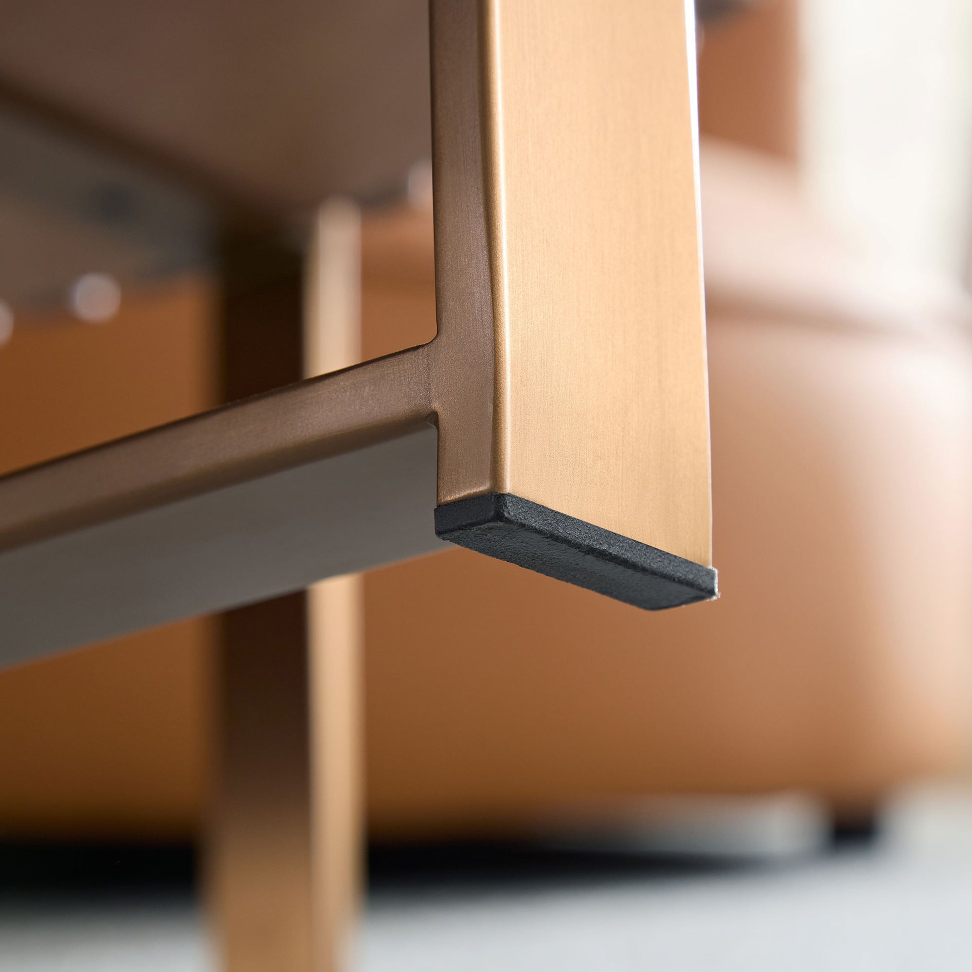 Closeup of gold metal table leg with black protective floor protector