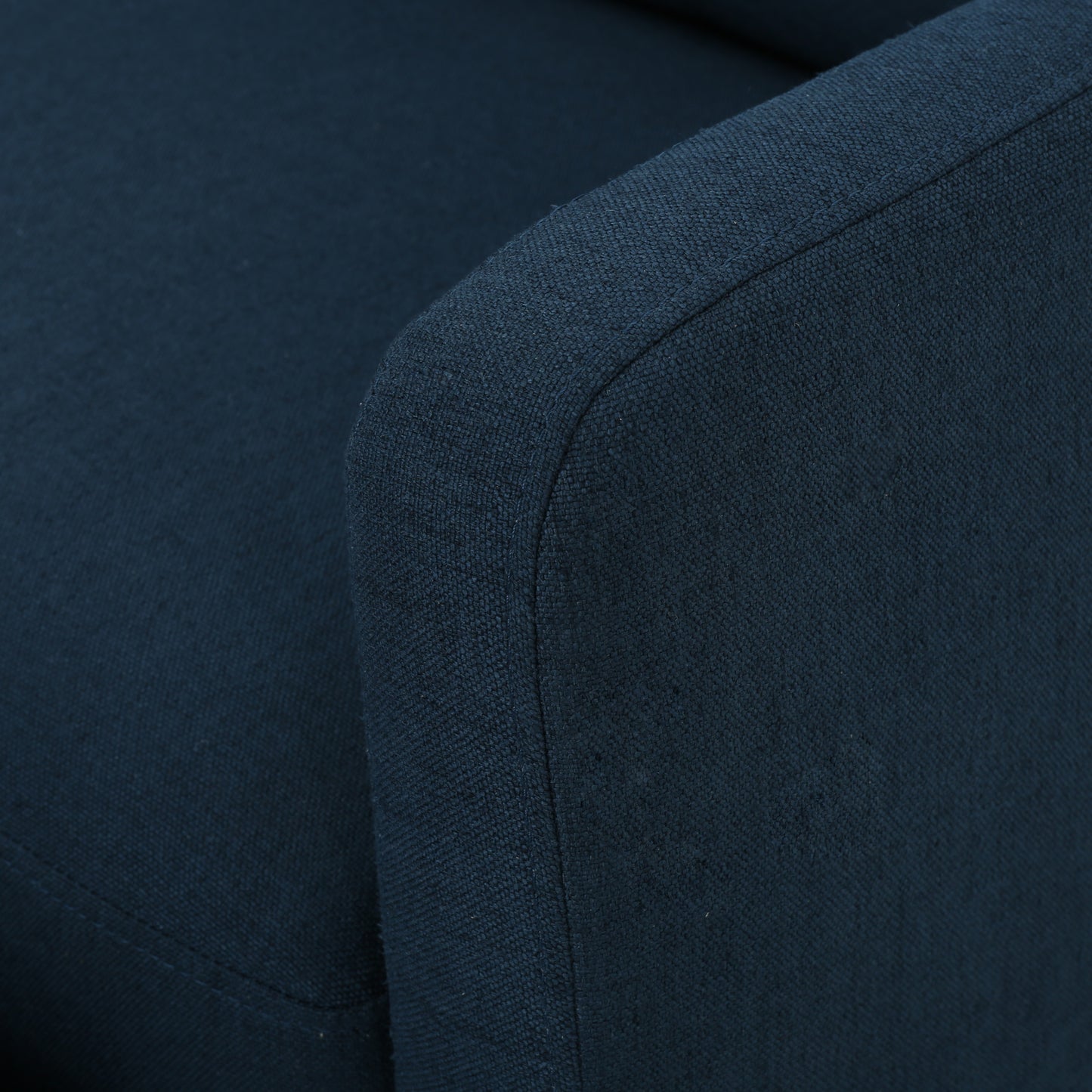 Closeup of a navy blue textured fabric sofa armrest with detailed stitching