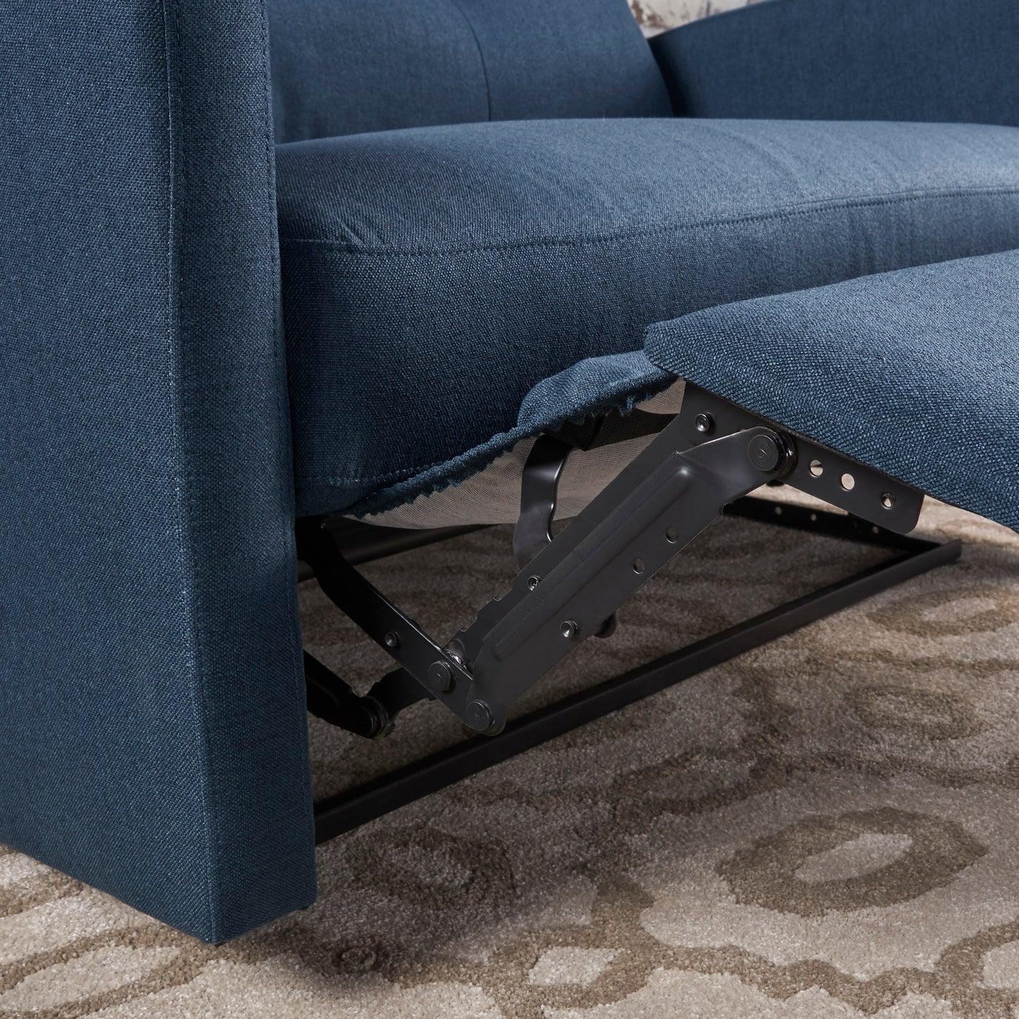 Closeup of navy blue fabric on a recliner sofa with visible metal reclining mechanism