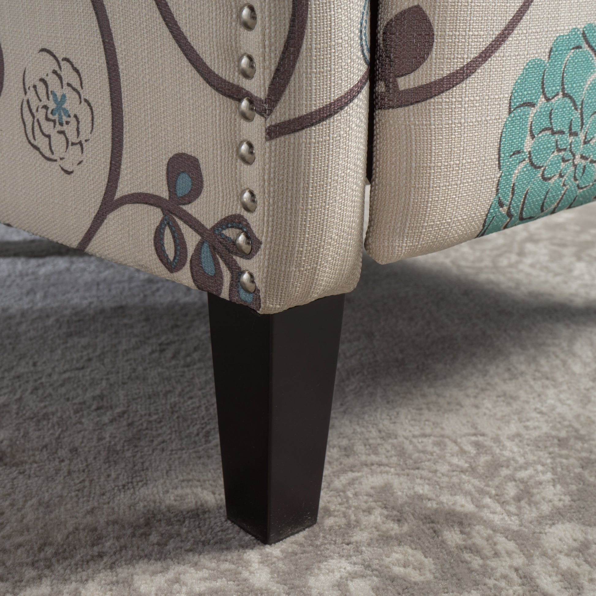 Beige upholstered armchair with floral pattern and dark wood legs