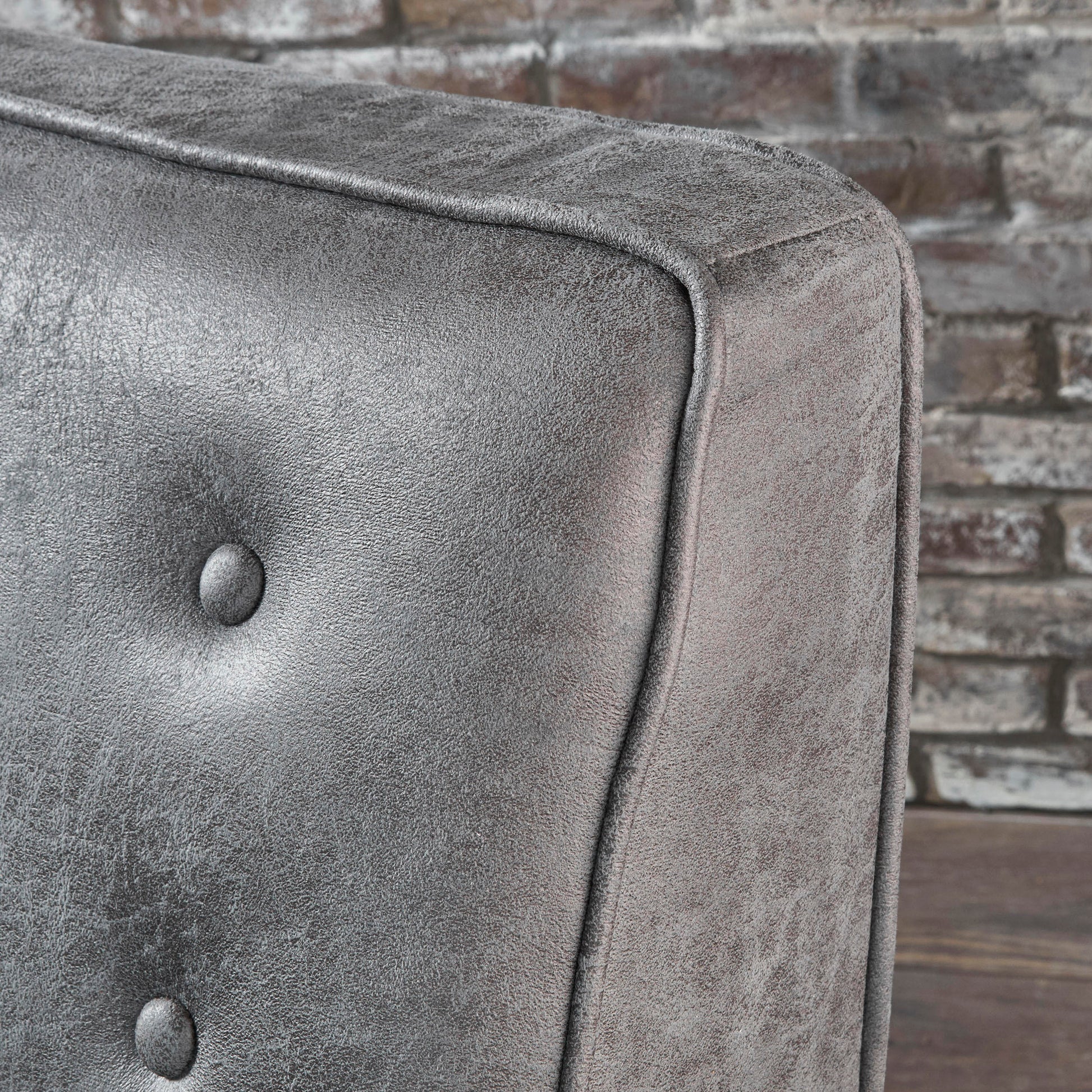 Closeup of charcoal tufted armchair upholstery with a distressed finish