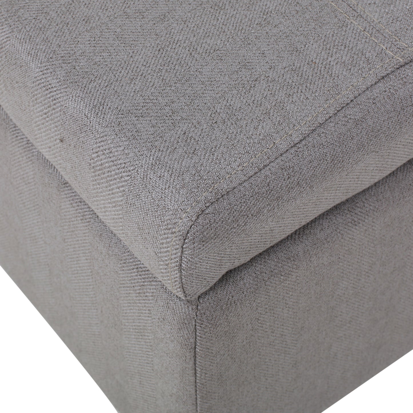 Closeup of grey fabric ottoman corner with textured weave and visible stitching