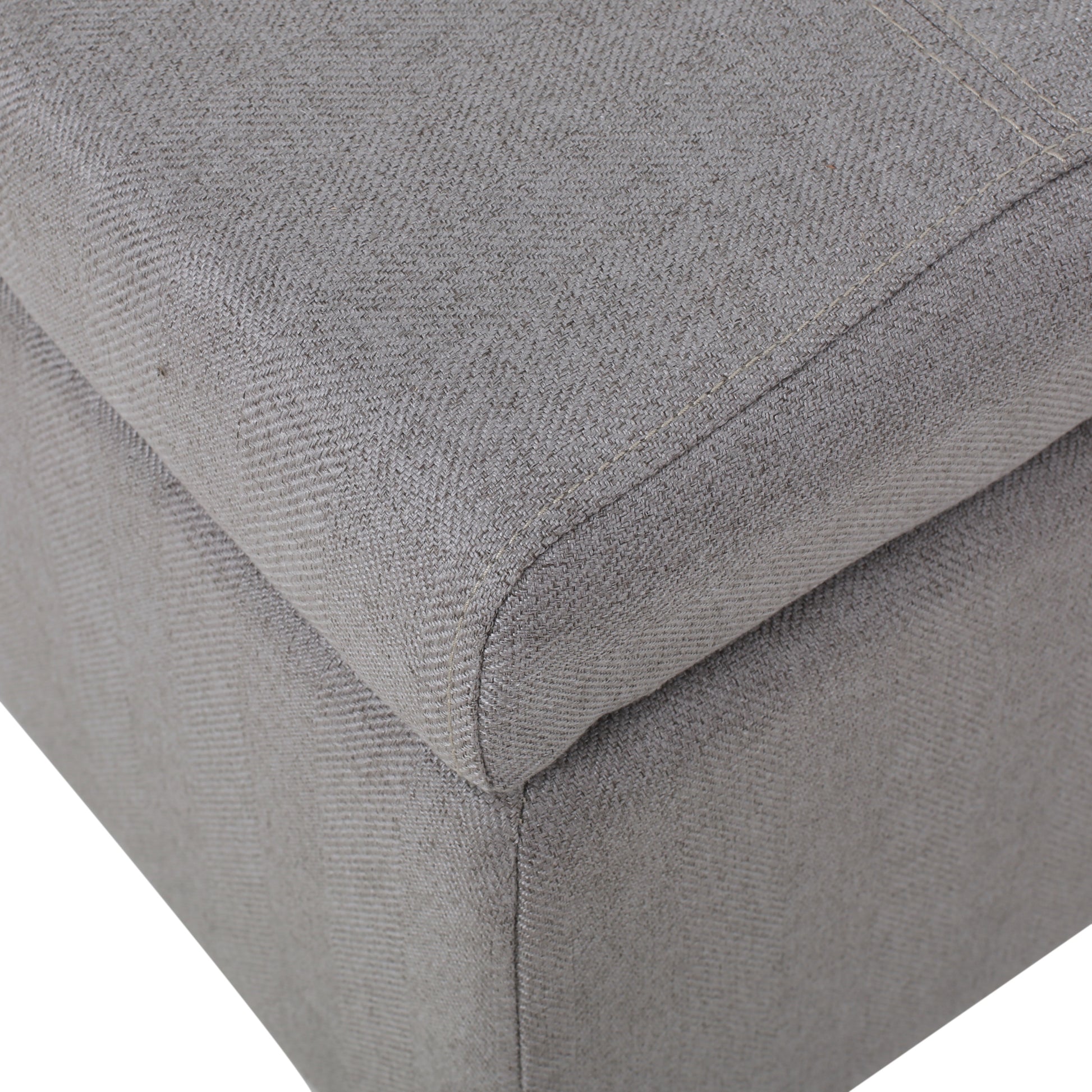 Closeup of grey fabric ottoman corner with textured weave and visible stitching
