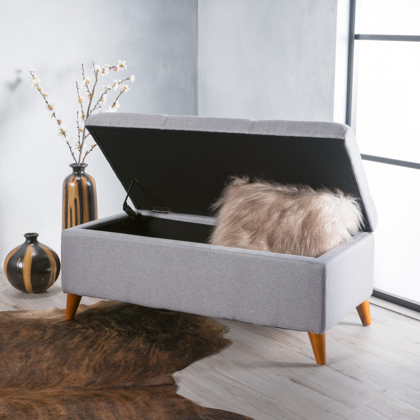 Grey upholstered storage ottoman with tufted lid perfect for a living room accent piece