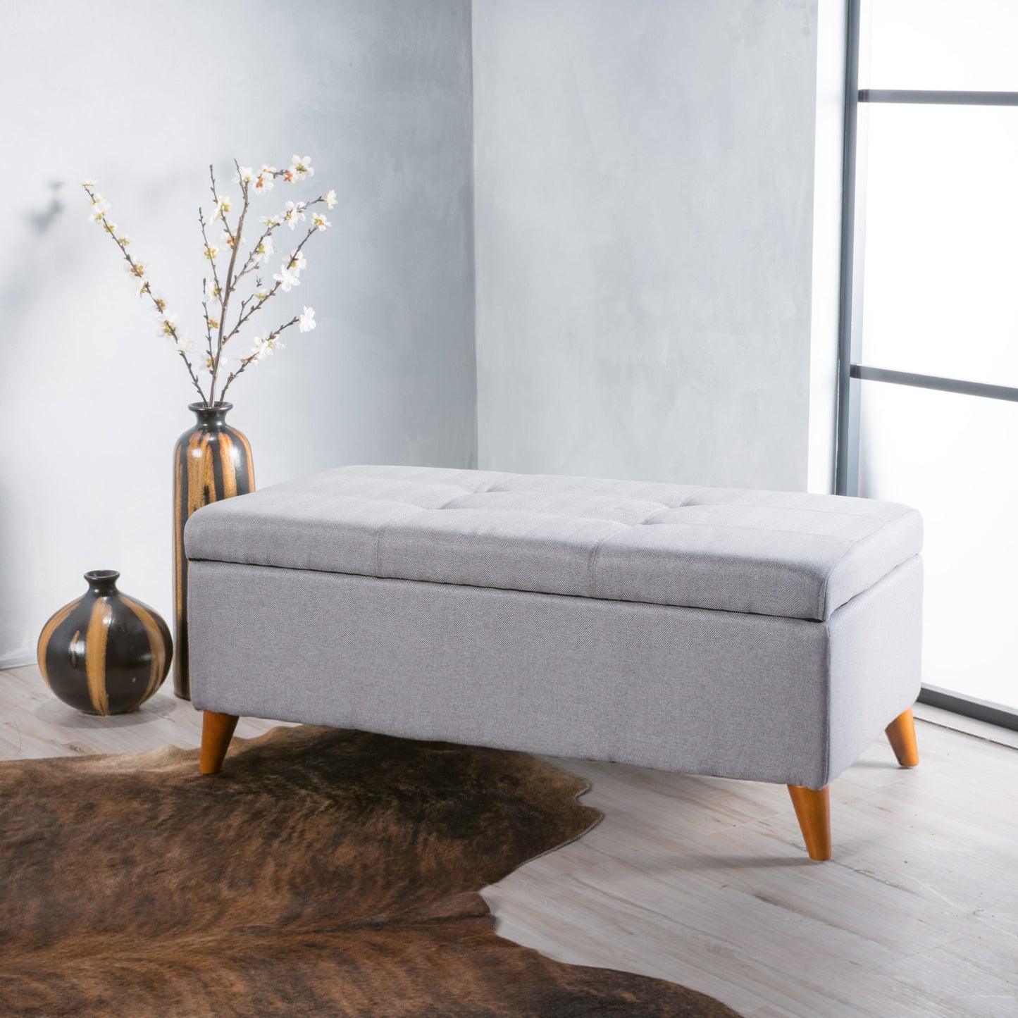 Tufted grey fabric storage bench with wooden tapered legs perfect for entryway seating