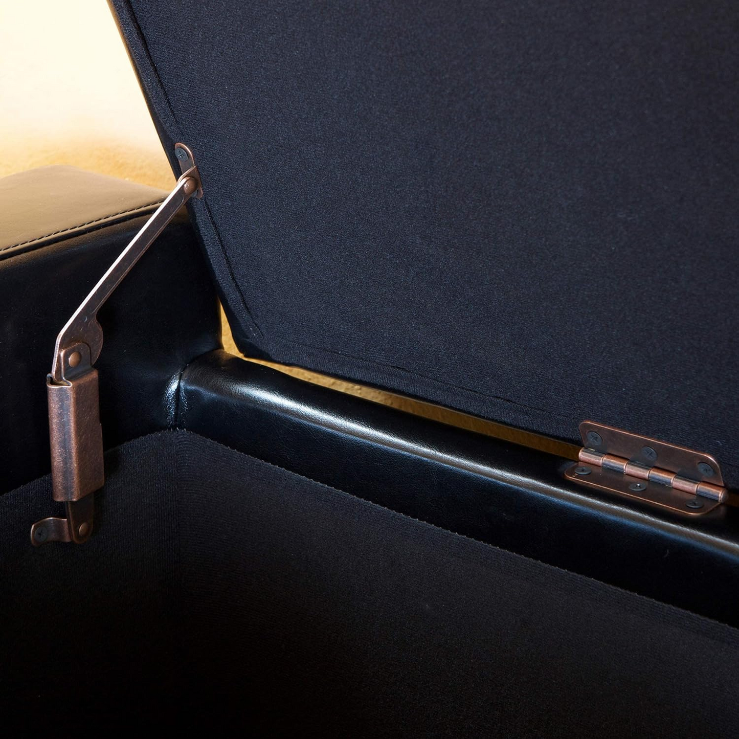 Black storage ottoman interior with copper antique hinge mechanism detail