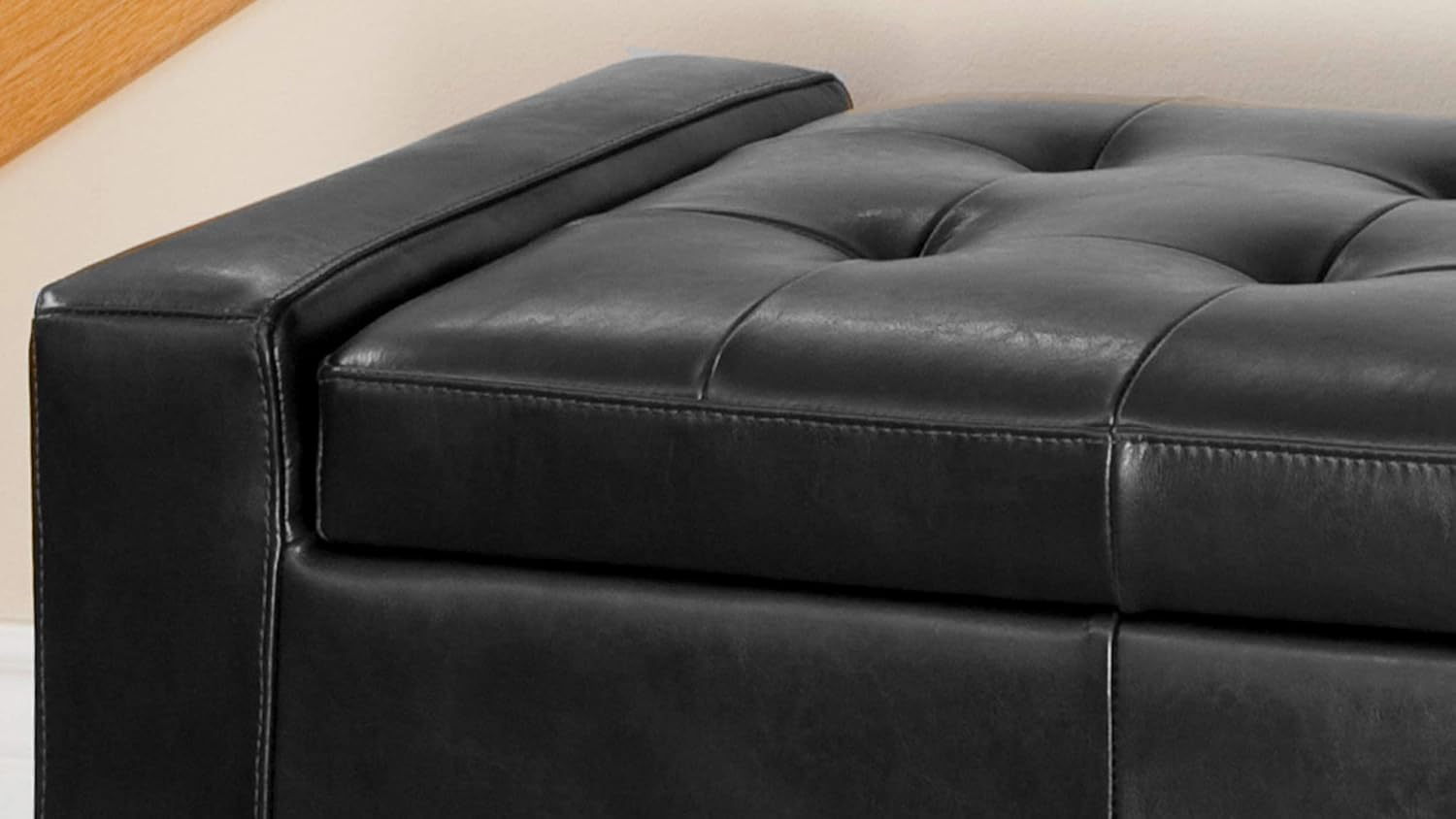 Black faux leather storage ottoman with tufted top and stitched details