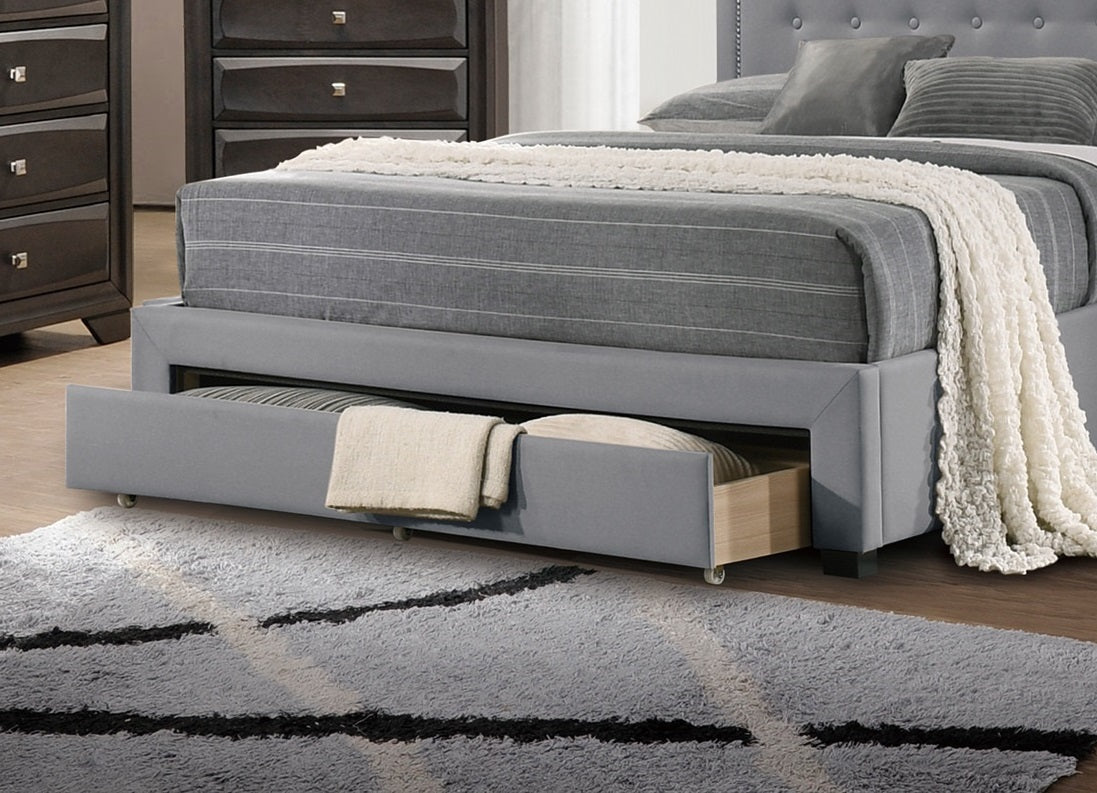 Gray upholstered bed frame with a pullout trundle drawer and striped bedding