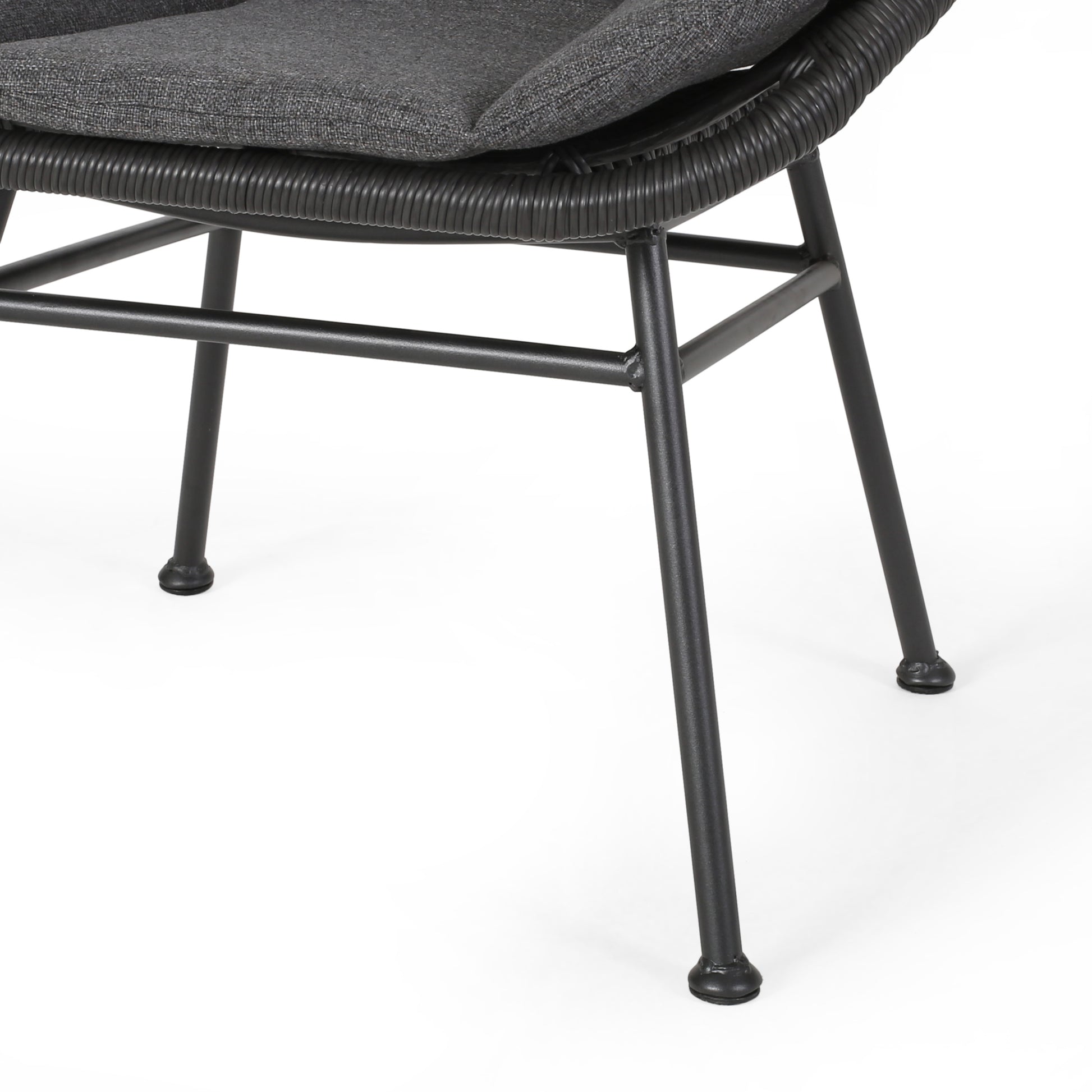 Closeup of gray upholstered chair seat and woven rattan base with black metal legs