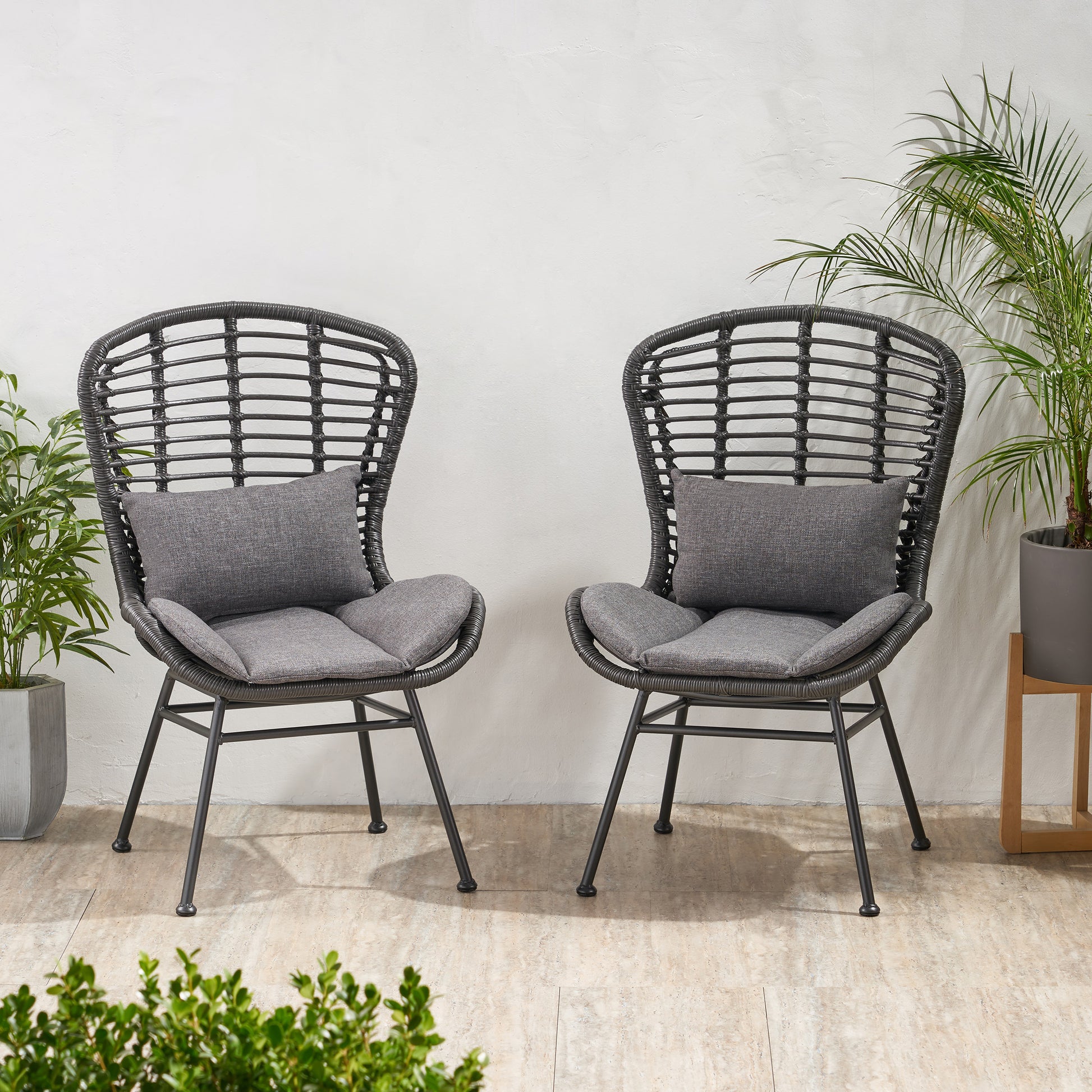 Two dark grey rattan outdoor chairs with grey cushions perfect for patio seating